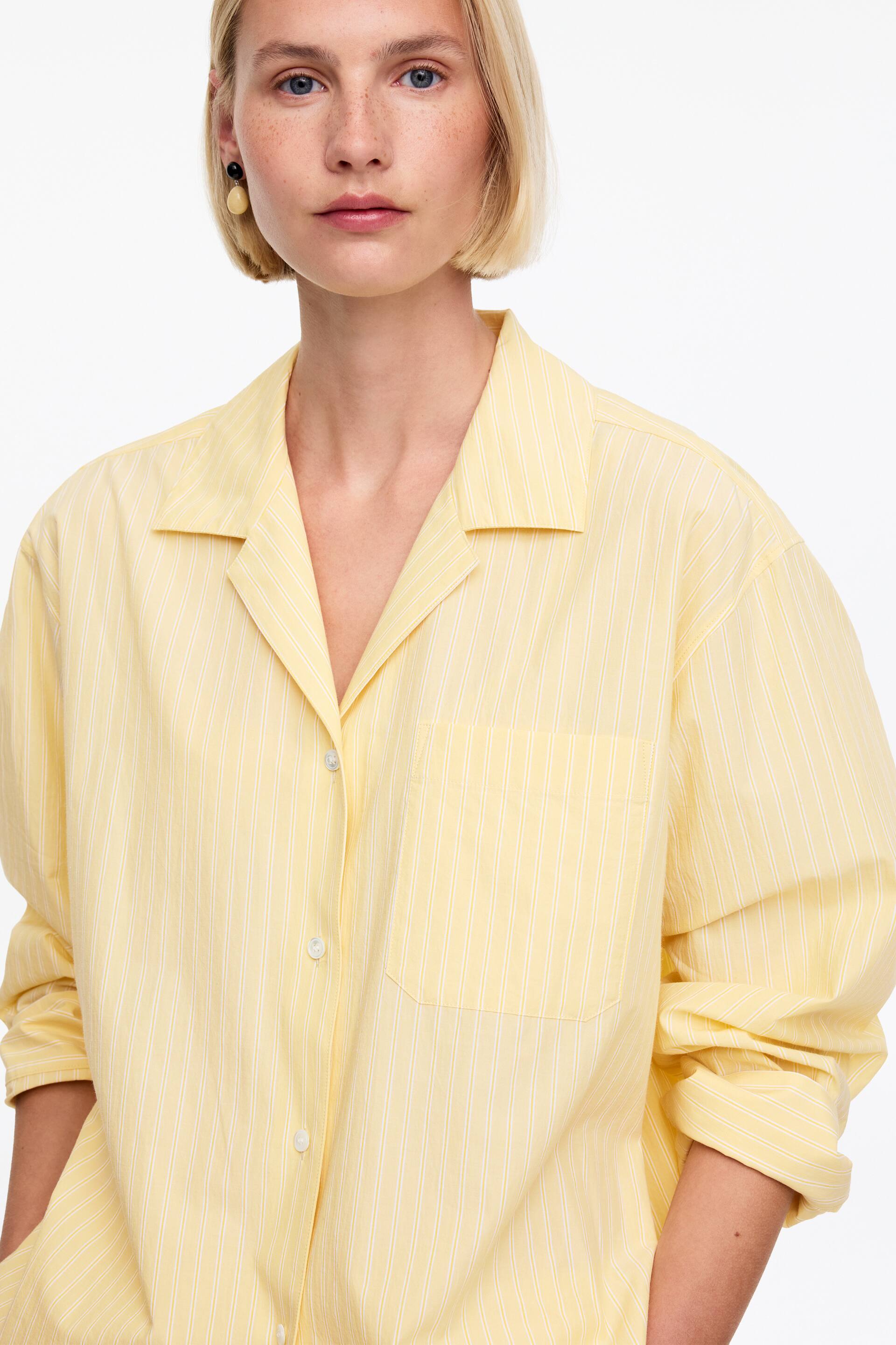 Ver imagen más grande: La modelo lleva puesta una camisa amarilla de gran tamaño con finas rayas verticales blancas. Presenta un cuello estilo resort, un bolsillo en el pecho y mangas largas con puños enrollados.