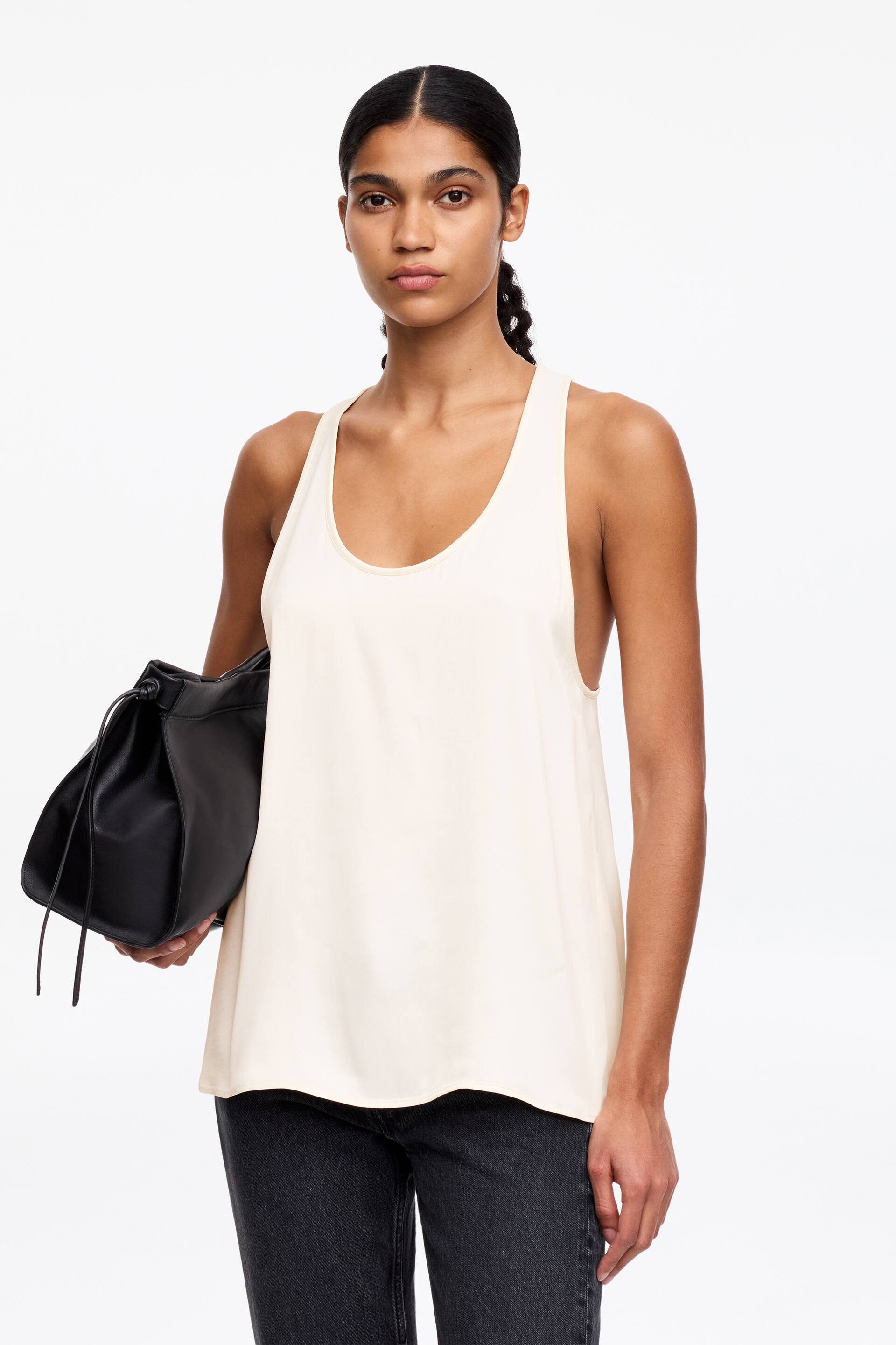 View larger image: An off-white tank top featuring a scoop neck and wide armholes, offering a relaxed, flowing fit with a straight hem.