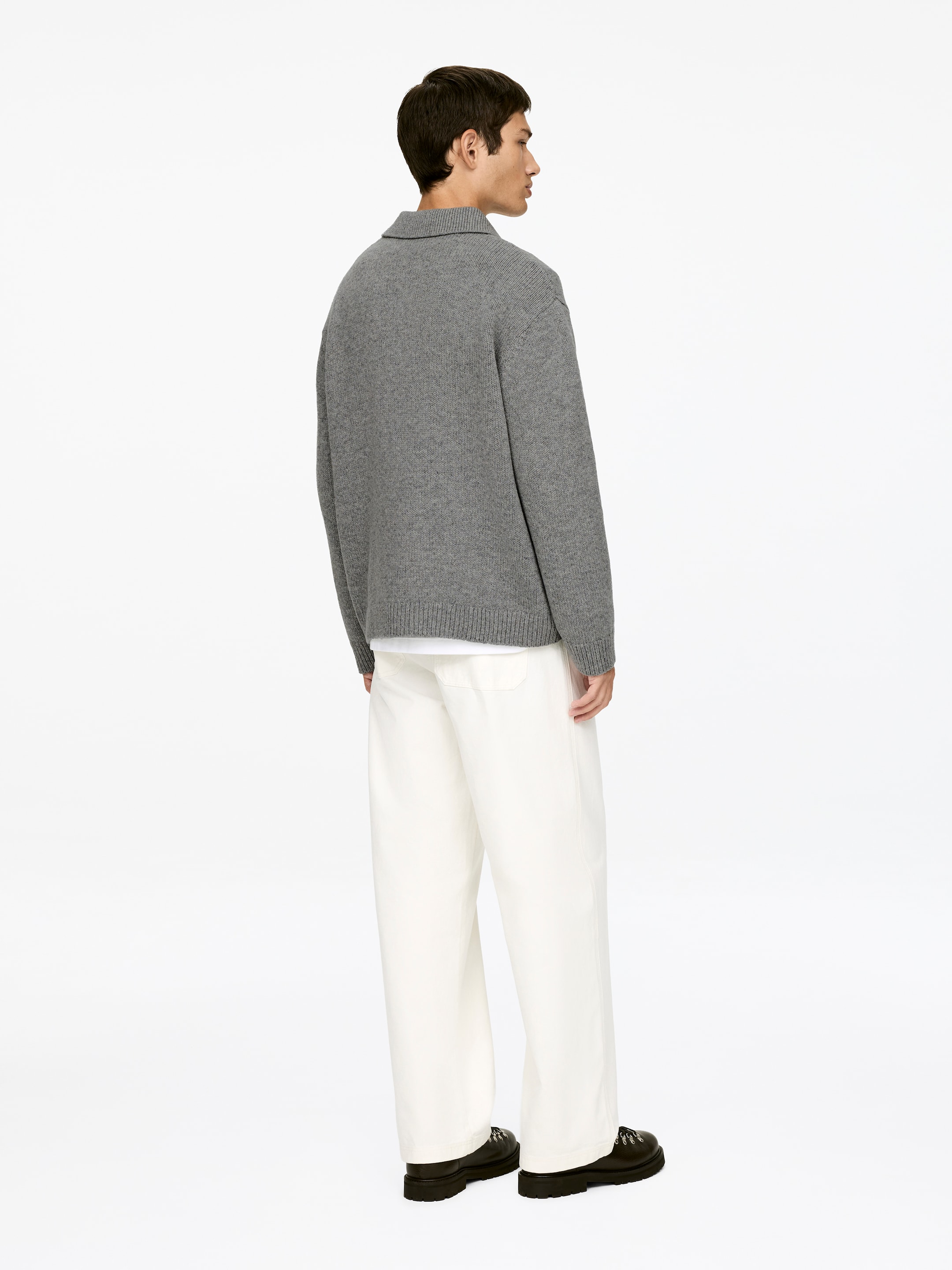 Agrandir l'image: Un pull gris ample et un pantalon large de couleur crème sont présentés de derrière du côté droit. Le pull gris présente un col pointu et un ourlet côtelé, avec un t-shirt blanc visible en dessous.