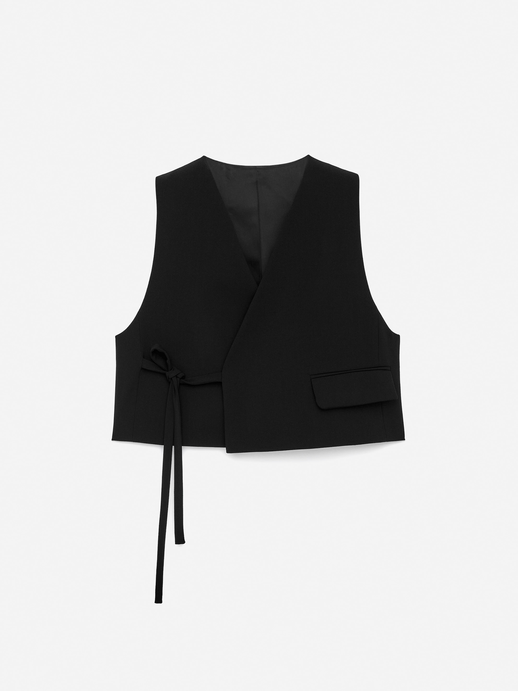 View larger image: A black tailored vest is shown from the front, featuring an overlapping design. It is secured on the left side by a tie strap, and a flap pocket is visible on the right.