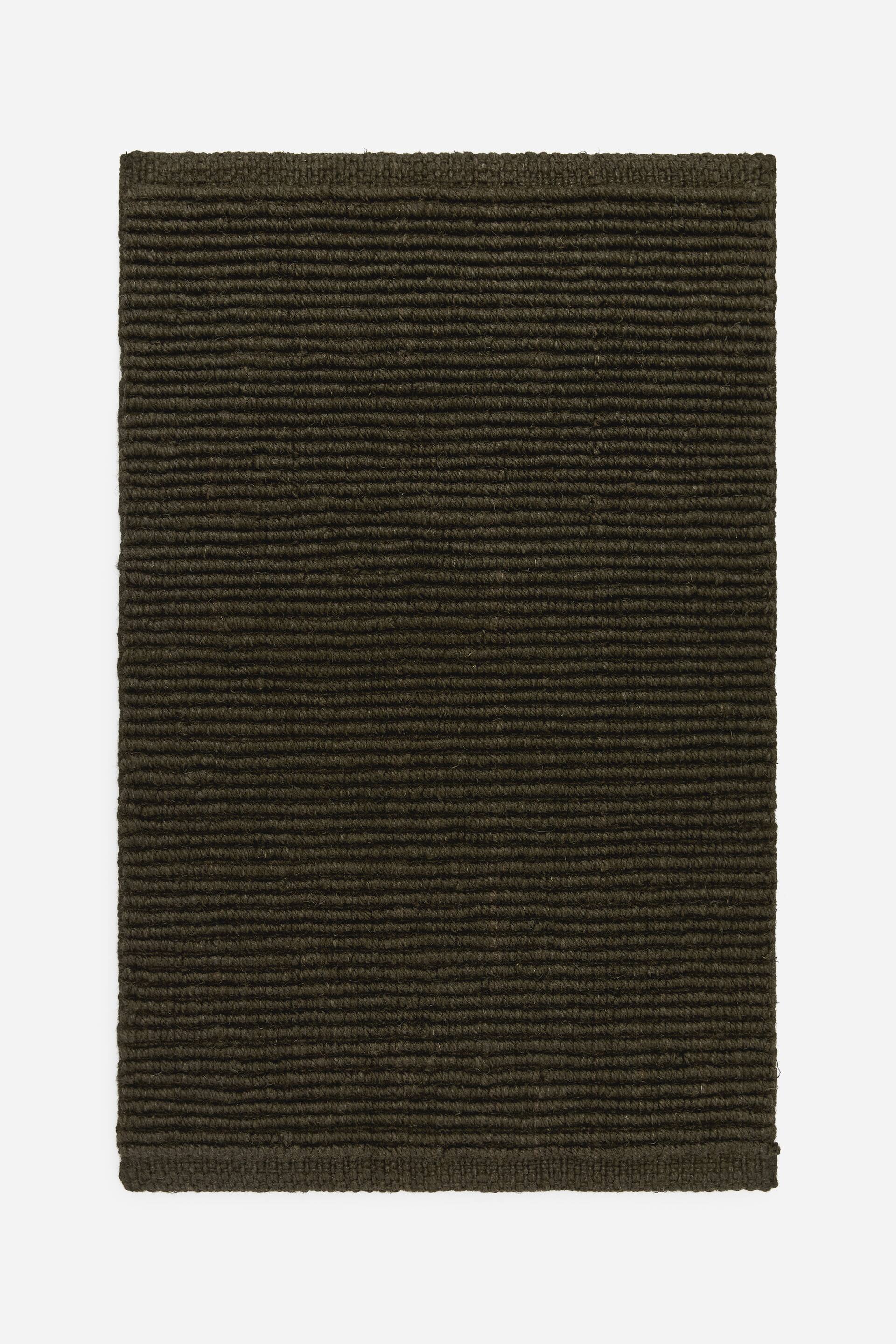 Visa större bild: En rektangulär mörk olivgrön matta visar sin FRAMSIDA, med en horisontellt ribbad struktur.