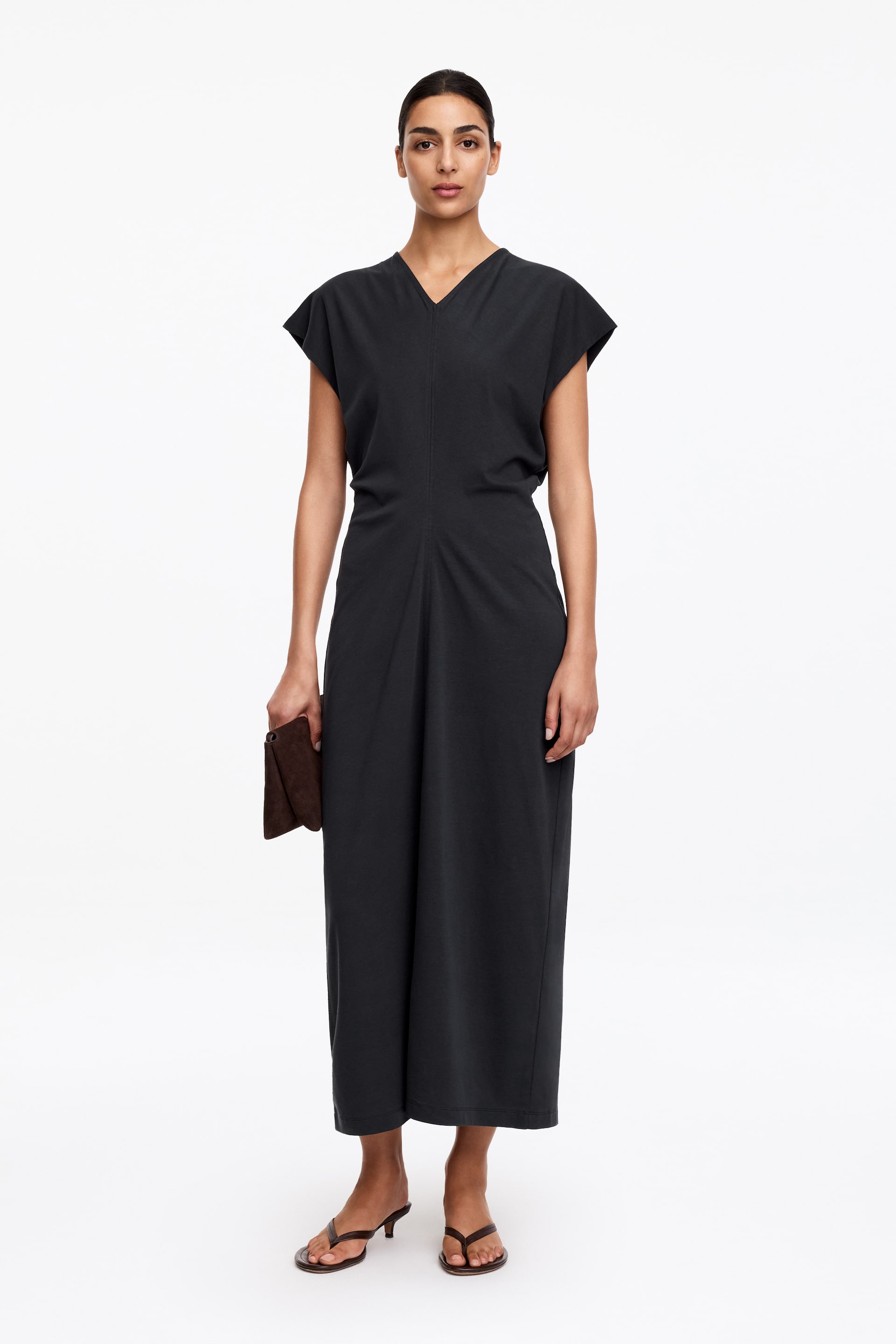 Agrandir l'image: Une robe midi gris foncé présente un décolleté en V et des manches courtes. Elle met en valeur un corsage ajusté avec une couture verticale centrale qui se prolonge en une jupe large et fluide, la robe étant orientée vers l'avant.