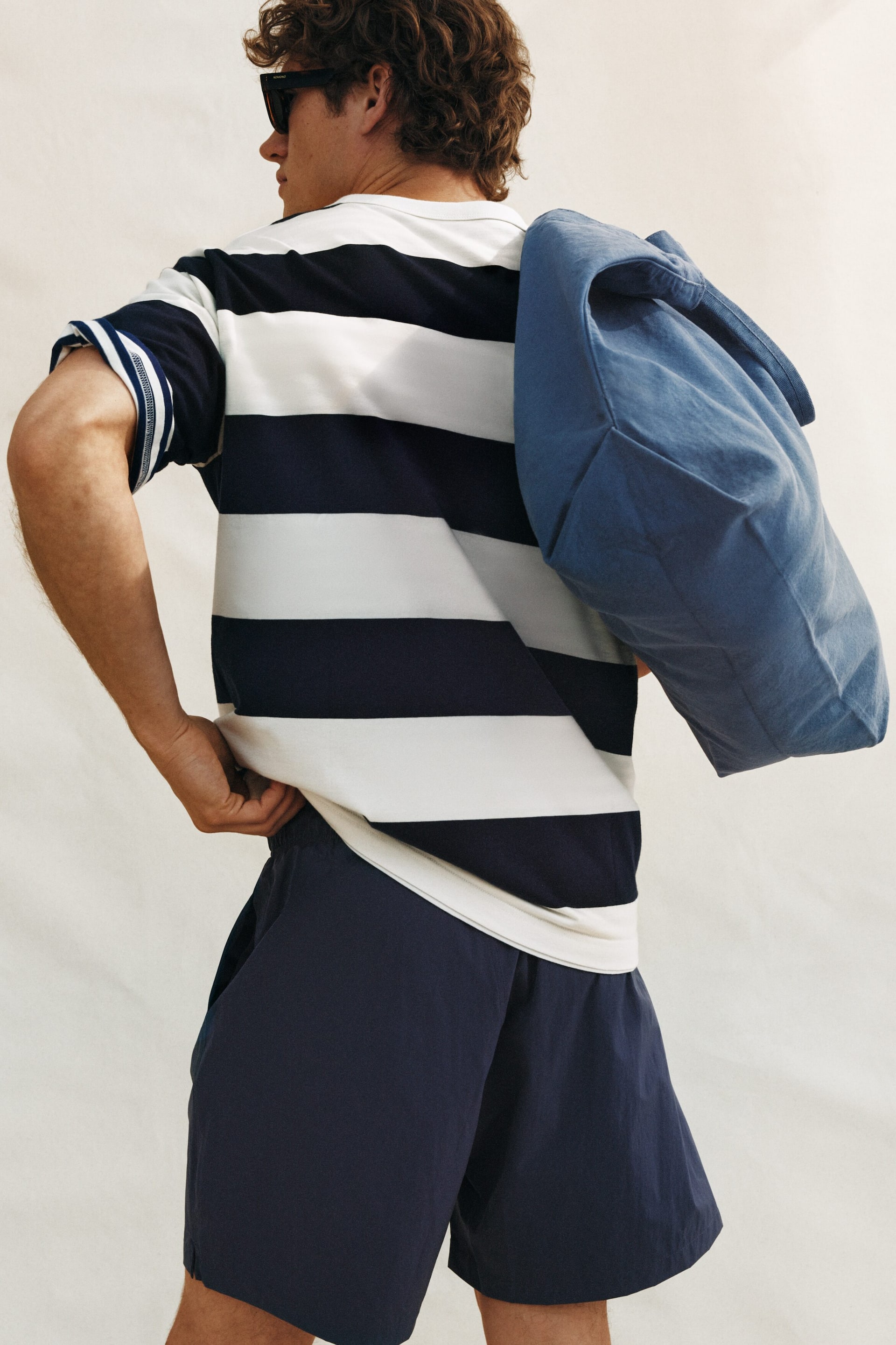 Ver imagem maior: Uma t-shirt às riscas exibe largas riscas horizontais em azul-marinho e branco. As suas mangas curtas apresentam punhos com riscas mais estreitas em azul-marinho e branco, e oferece um corte descontraído na parte de trás.