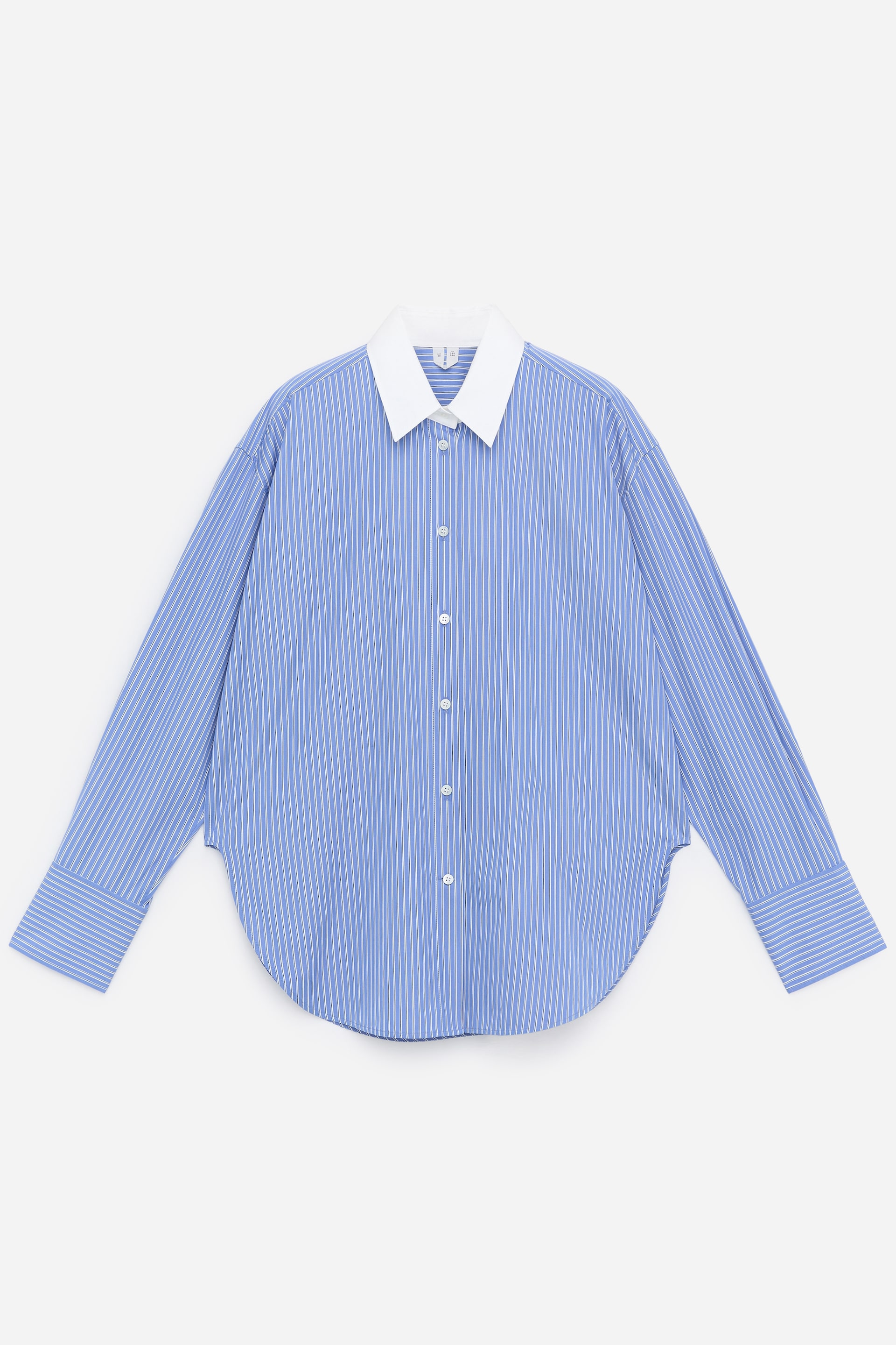 Ver imagen más grande: Una camisa de manga larga, confeccionada en un popelín de algodón fresco, se presenta desde el FRENTE. Este estilo abotonado presenta un patrón de rayas verticales azules y blancas, un cuello puntiagudo blanco en contraste, botones frontales blancos, puños anchos y un dobladillo curvado, mostrando una silueta relajada pero elegante.
