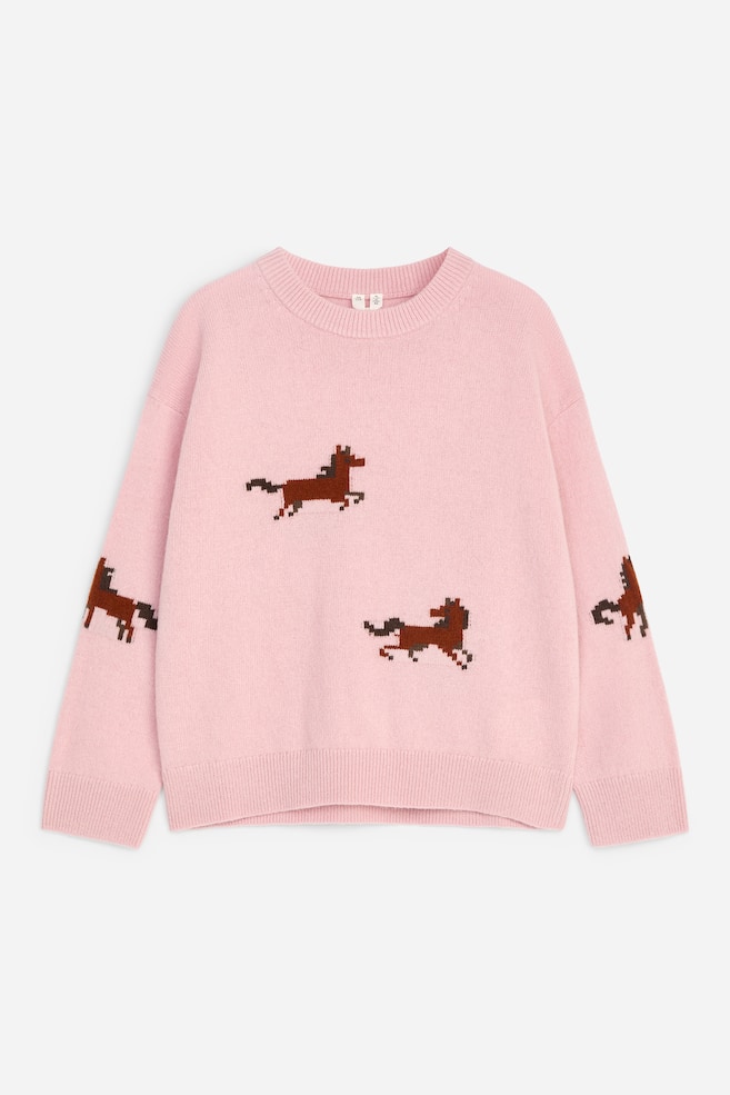 Un maglione girocollo in maglia rosa è mostrato frontalmente, con motivi a cavallo marrone in stile pixel sparsi sul petto e sulle maniche. Presenta una vestibilità rilassata con spalle scese, collo a costine, polsini a costine e orlo a costine. - 1