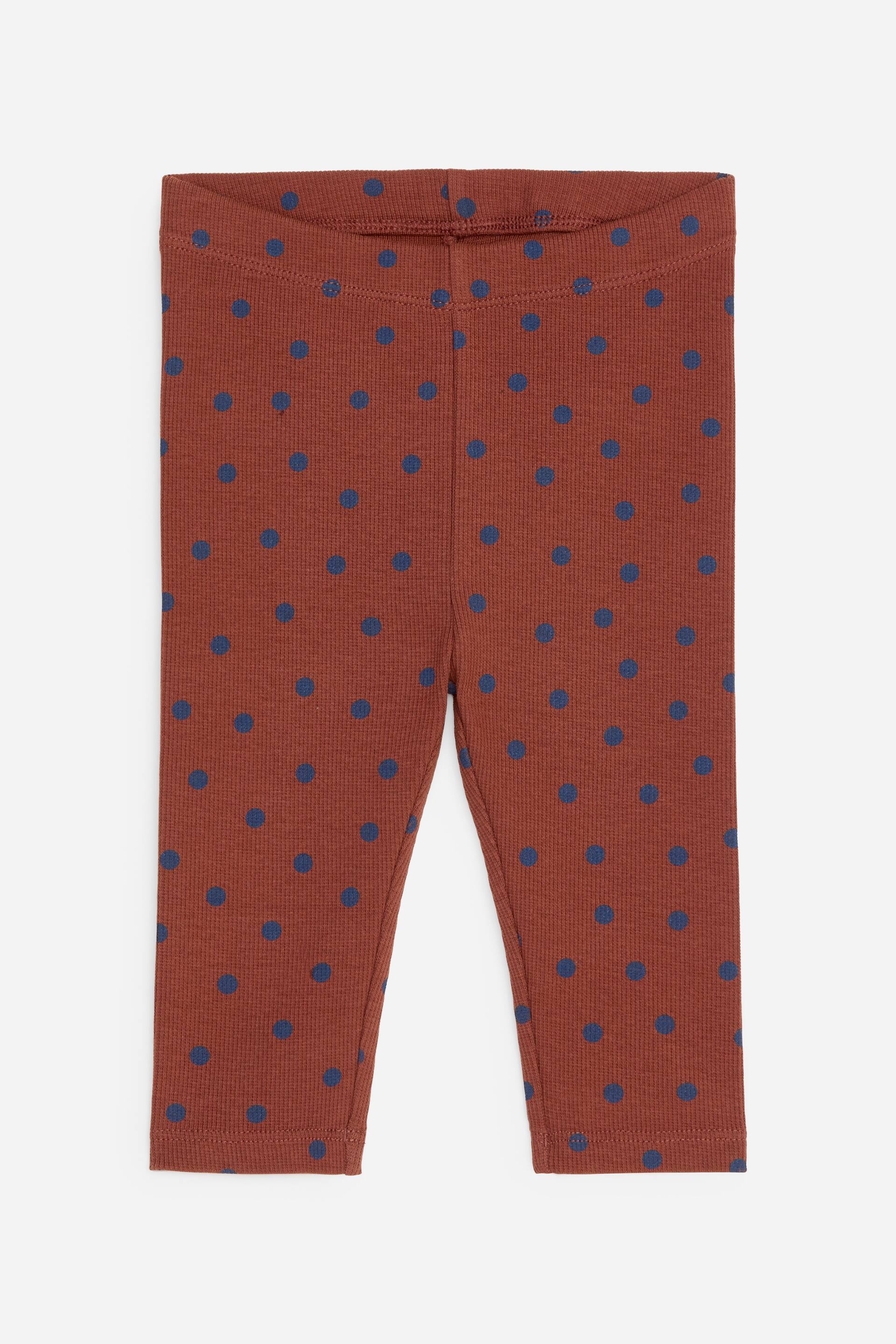 Agrandir l'image: Les leggings en maille côtelée sont présentés de face, arborant une couleur brun-rouge avec un motif à pois bleus sur l'ensemble. Une ceinture élastiquée est visible en haut.