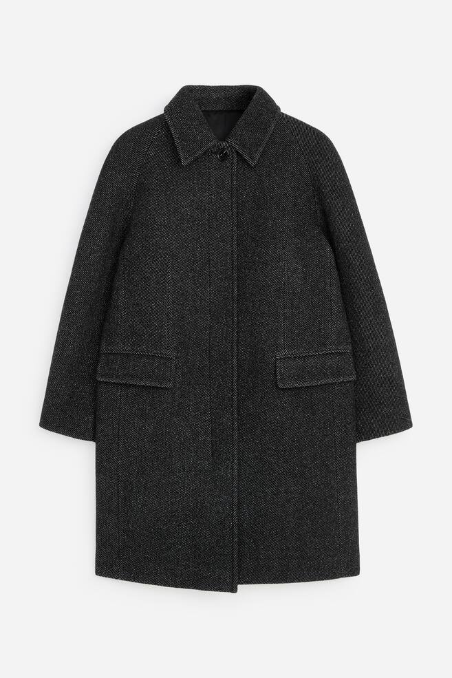 A dark grey, textured wool-blend coat is shown from the front, featuring a pointed collar with a single visible top button and a concealed front placket. The coat has raglan sleeves, a straight silhouette, and two front flap pockets. - 1