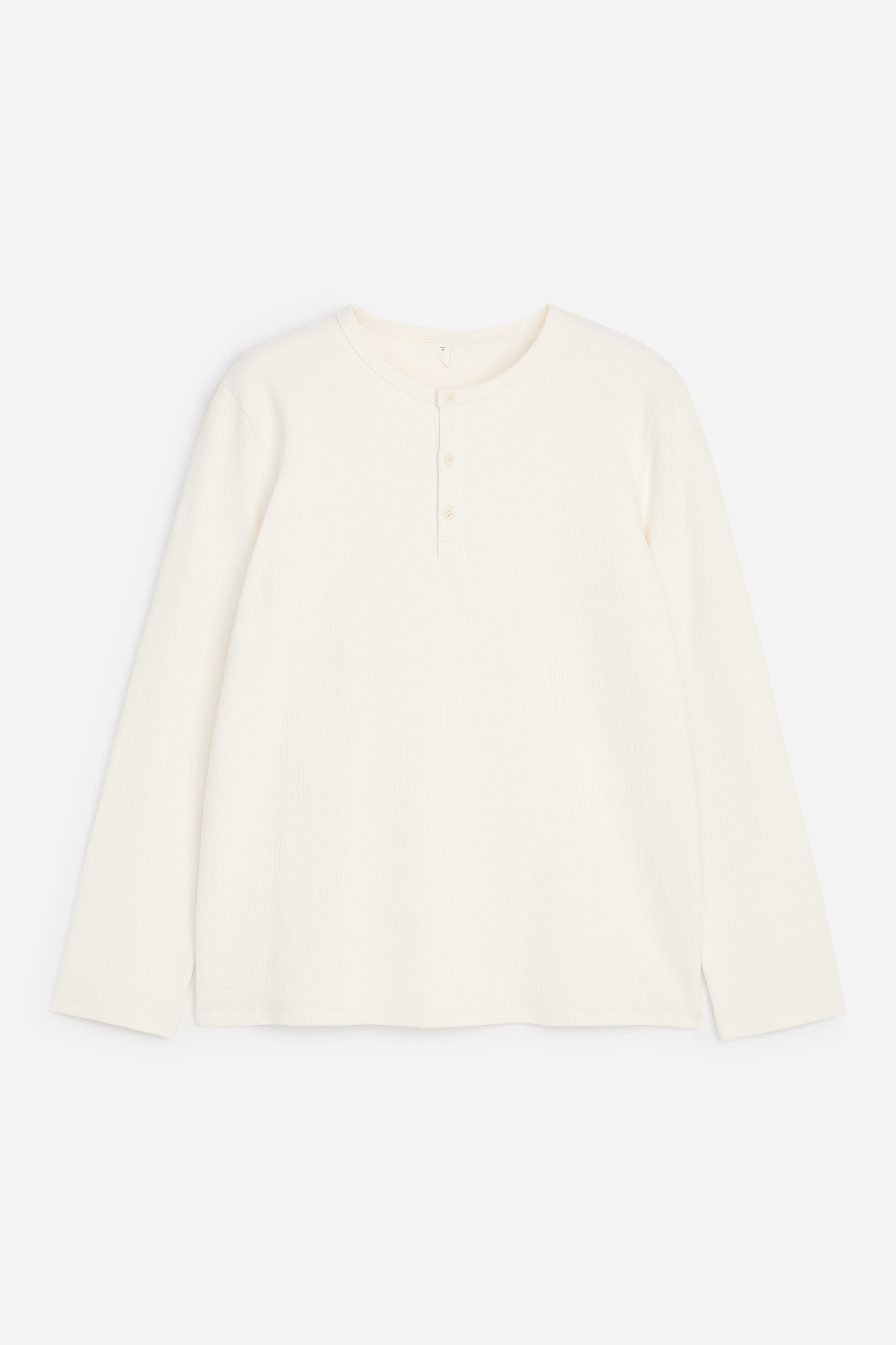 Ver imagen más grande: Una camisa Henley de color blanco roto muestra su vista frontal. Está confeccionada en un jersey de algodón de punto canalé, con mangas largas, un ribete acanalado en el cuello y una tapeta corta con tres botones a juego.