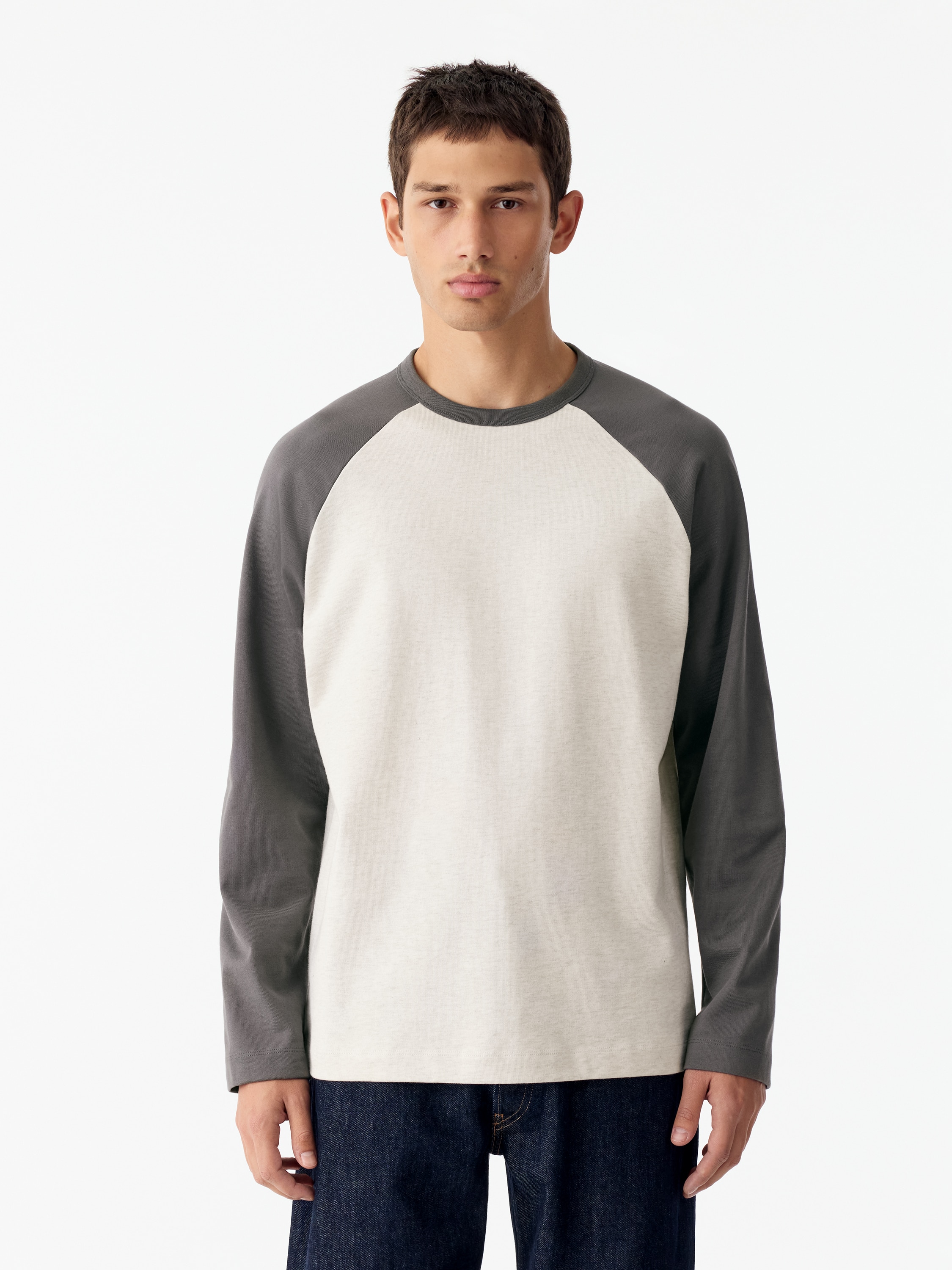 Vista frontale di una T-shirt da baseball che presenta un classico design color block con corpo grigio chiaro testurizzato e maniche raglan lunghe grigio scuro a contrasto. La maglietta Ã¨ dotata di girocollo a costine grigio scuro abbinato e orlo dritto.