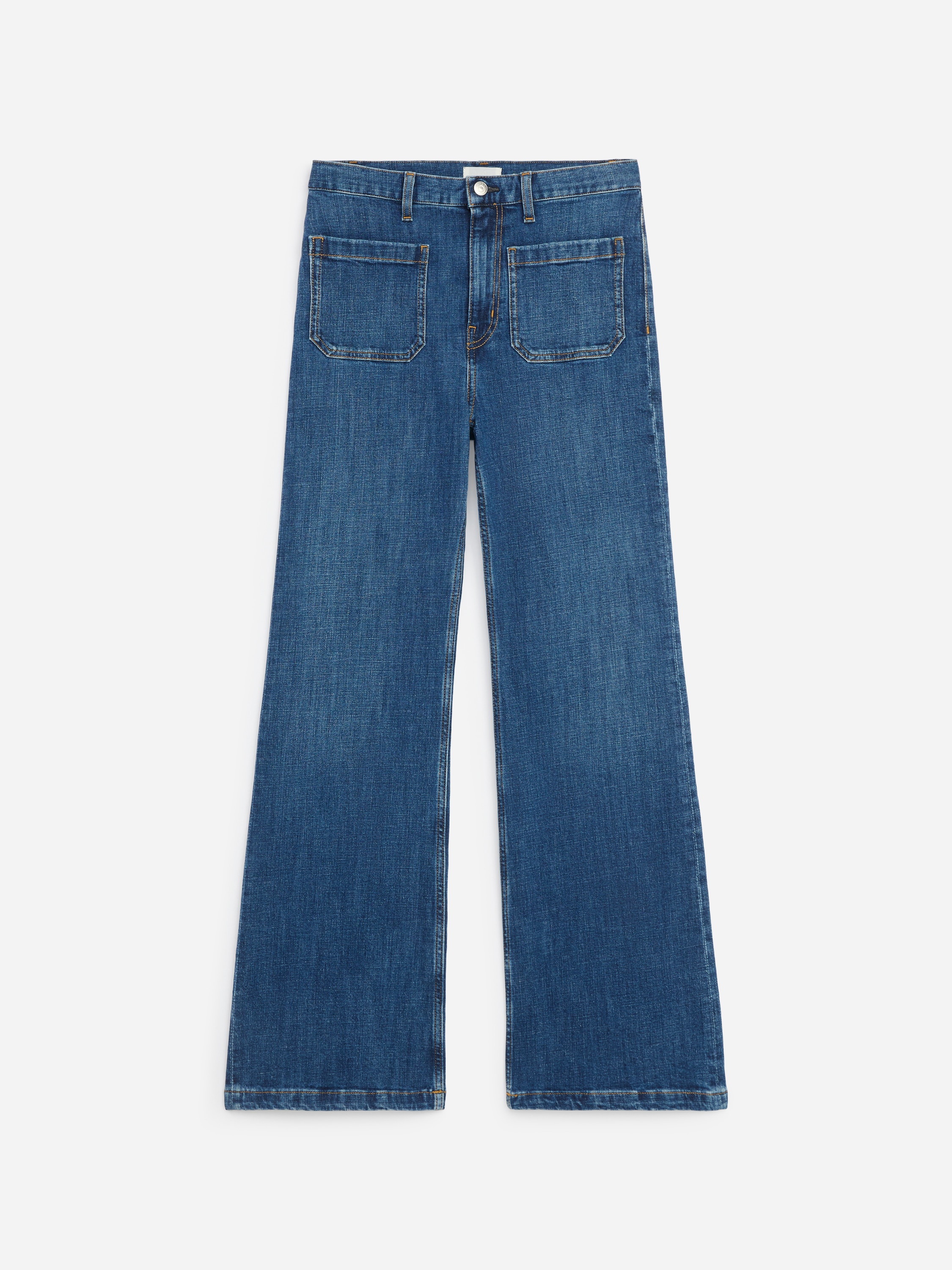 La modella indossa jeans in denim blu con vita alta, tasche applicate sul davanti e gamba svasata. I jeans sono abbinati a una maglietta a costine blu scuro a maniche corte, infilata Ø¯Ø§Ø®Ù.