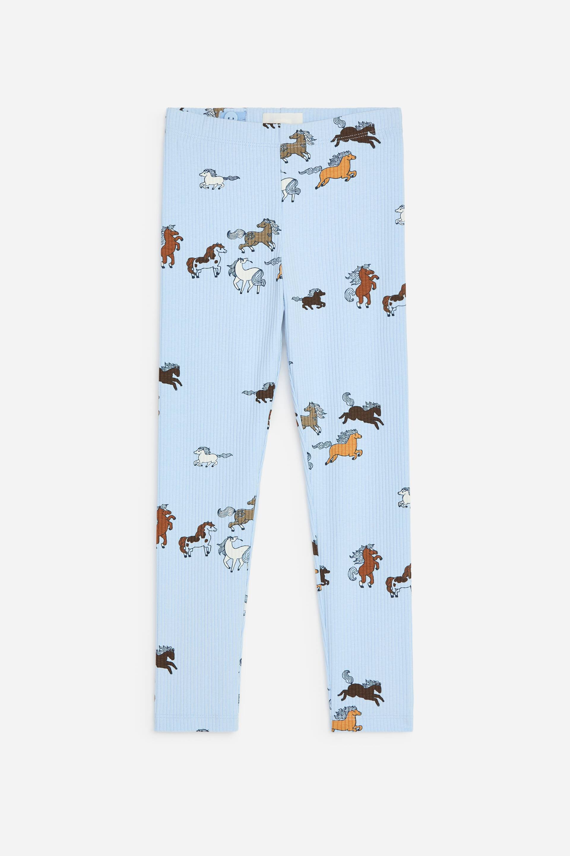 View larger image: This pair of light blue ribbed leggings is shown from the front, showcasing an all-over print of horses in various colours and active poses. The leggings feature an elastic waistband and a slim-fit, full-length design.