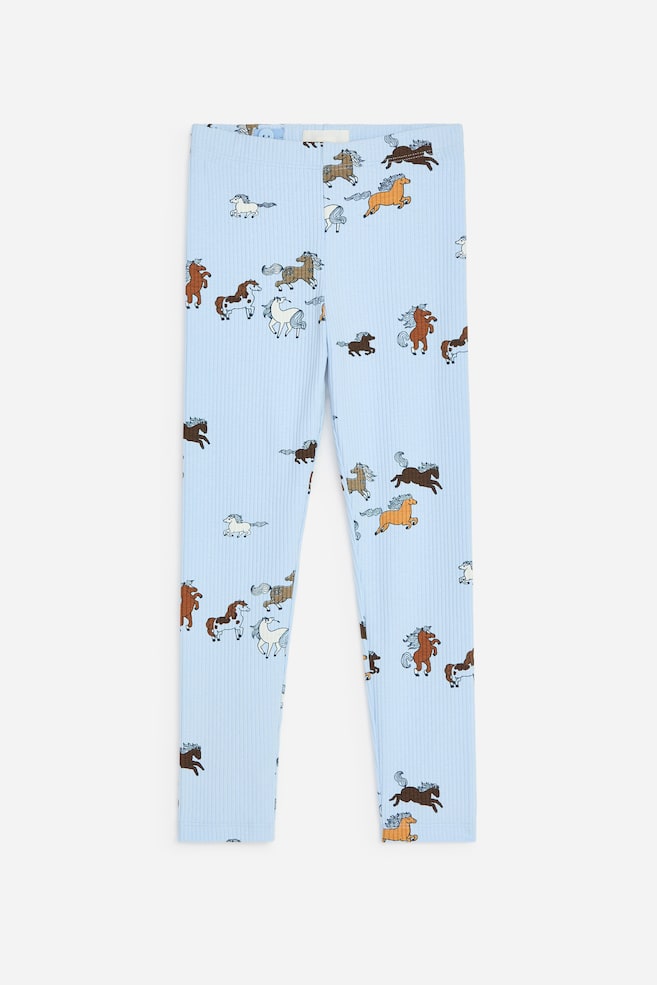 Dieses Paar hellblauer, gerippter Leggings ist von vorne zu sehen und zeigt einen Allover-Print mit Pferden in verschiedenen Farben und dynamischen Posen. Die Leggings verfügen über einen elastischen Bund und eine schmale, lang geschnittene Passform. - 1