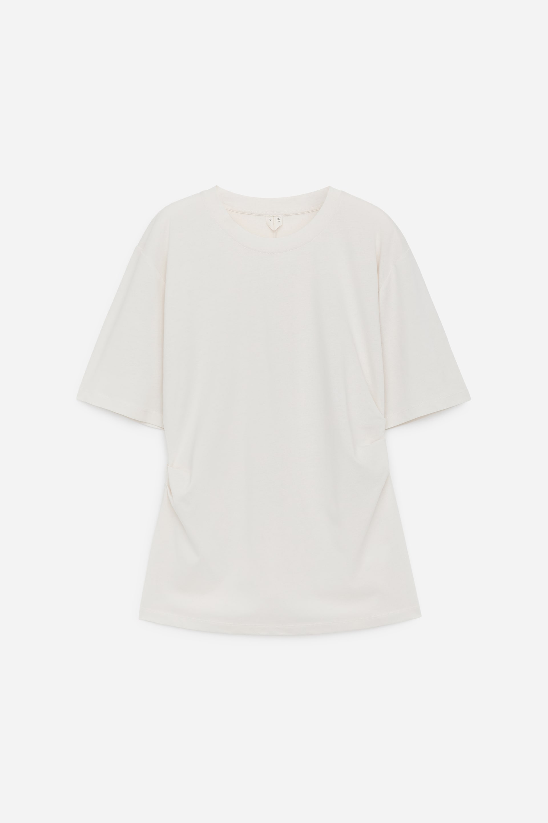 Grösseres Bild ansehen: Ein cremefarbenes T-Shirt präsentiert seine Vorderseite, mit einem Rundhalsausschnitt und kurzen, breiten Ärmeln. Der oversized Schnitt erzeugt weiche Falten an den Seiten, was auf einen entspannten Fall hinweist.