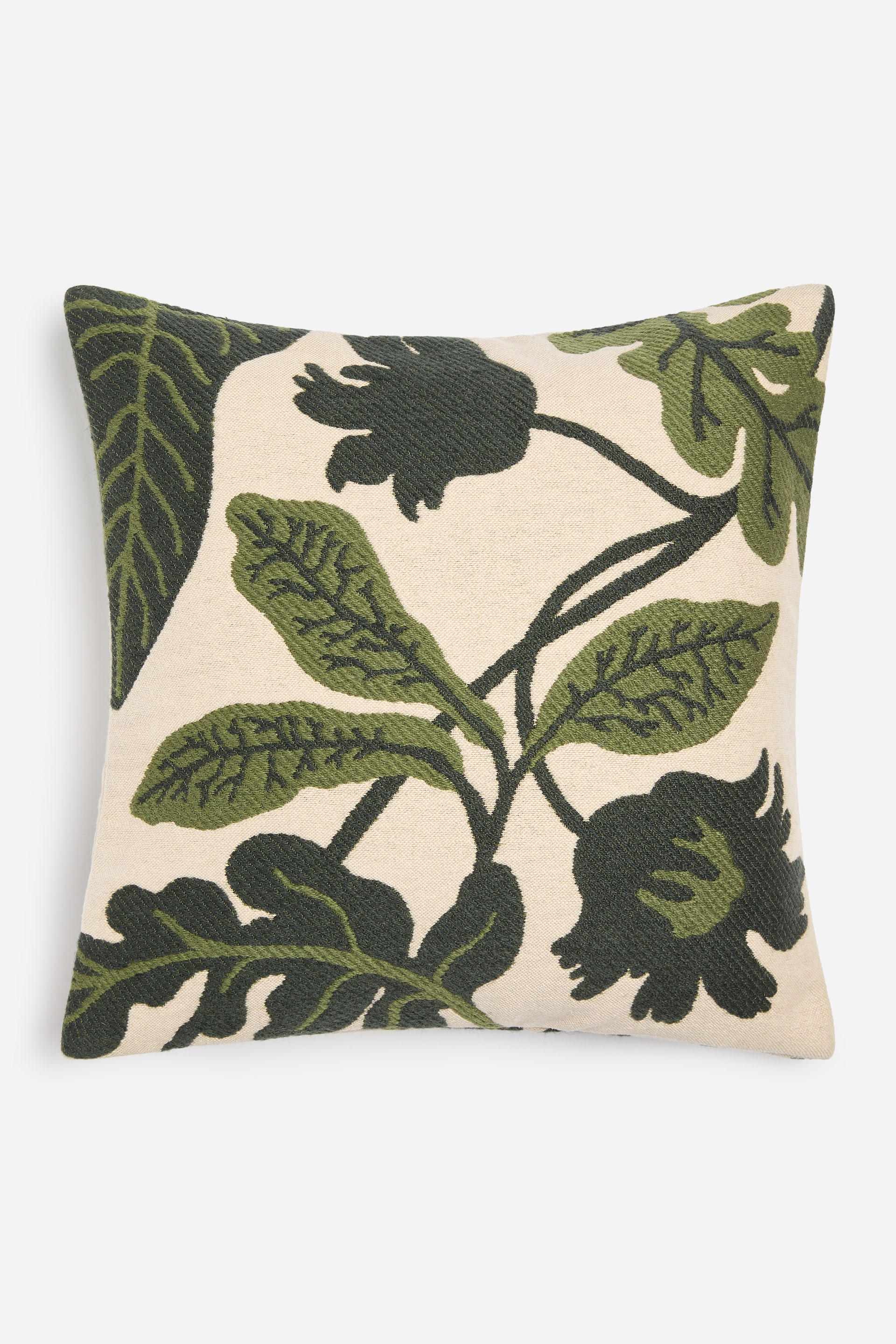 Ver imagen más grande: Un cojín cuadrado presenta un fondo crema con un gran estampado botánico. El estampado muestra hojas y formas florales abstractas en dos tonos de verde, verde oscuro y un verde musgo más claro, distribuidos por toda su superficie frontal.