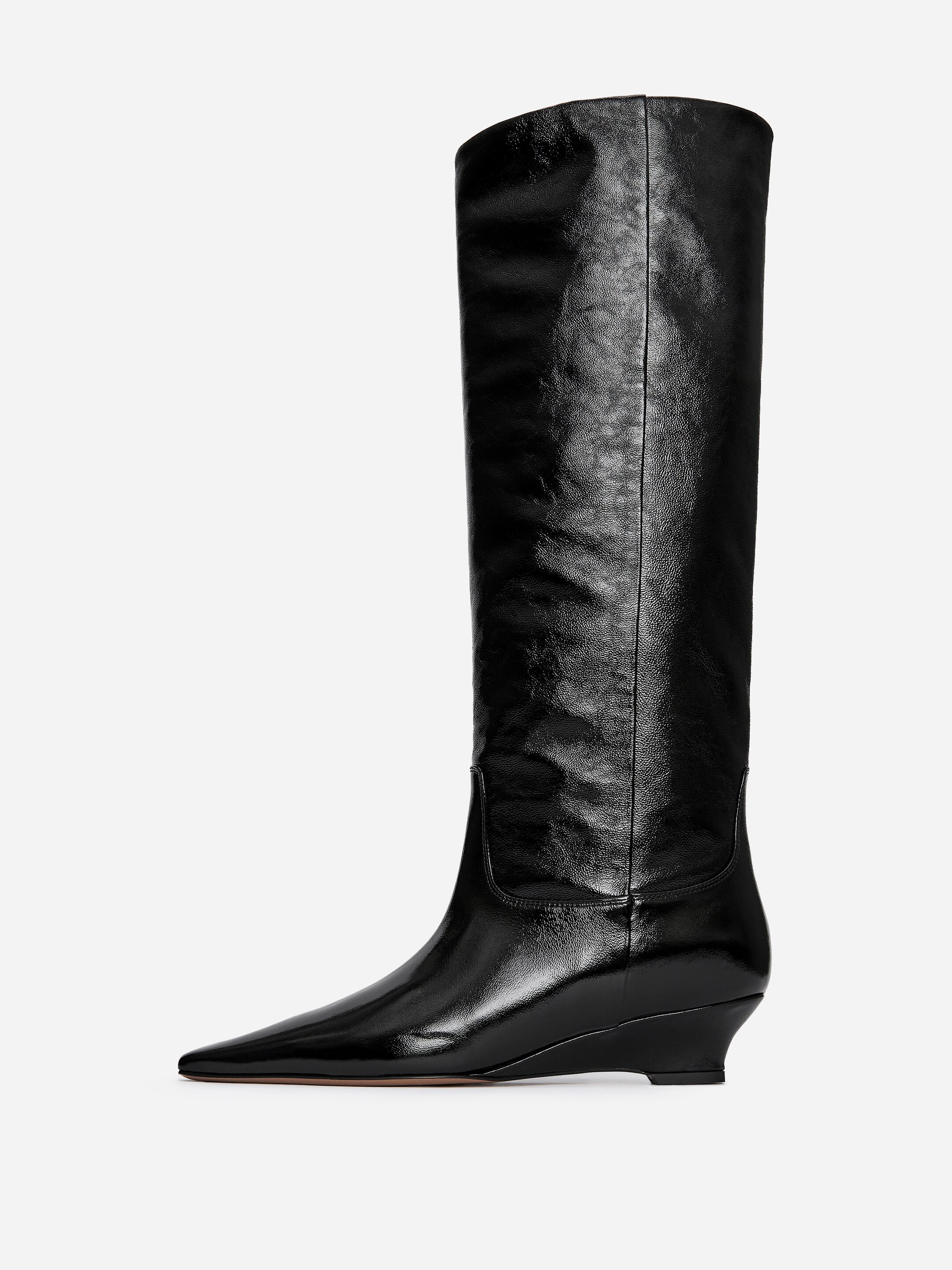 Agrandir l'image: Une botte en cuir noir et lustré est présentée, orientée vers la droite, et se caractérise par une tige haute subtilement texturée, un bout pointu et un talon compensé bas.