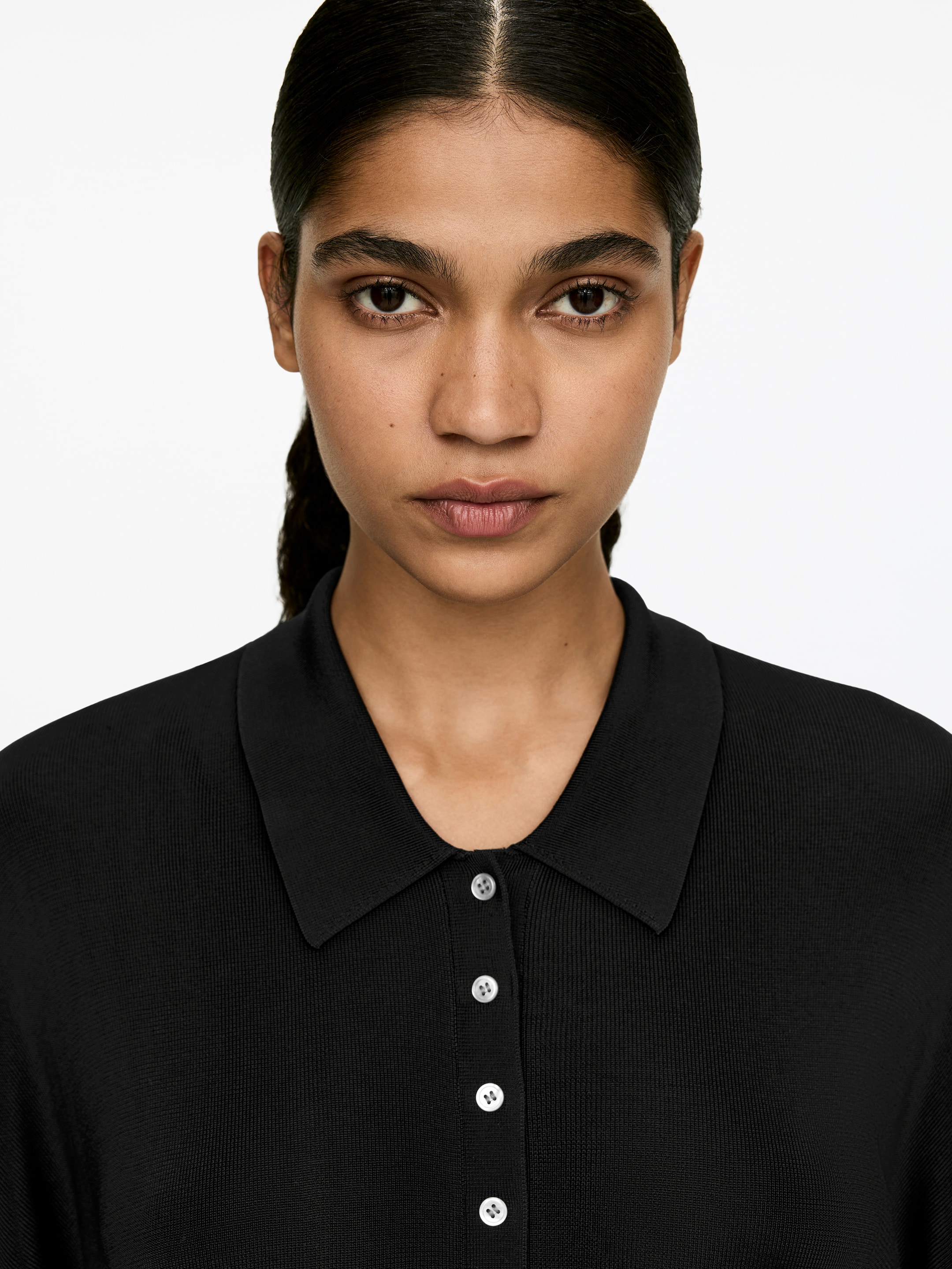 Visa större bild: En svart finstickad viskos skjorta, med en klassisk skjortkrage och en vit knappstängning, bärs av modellen. Modellen bär skjortan med den översta knappen knäppt.