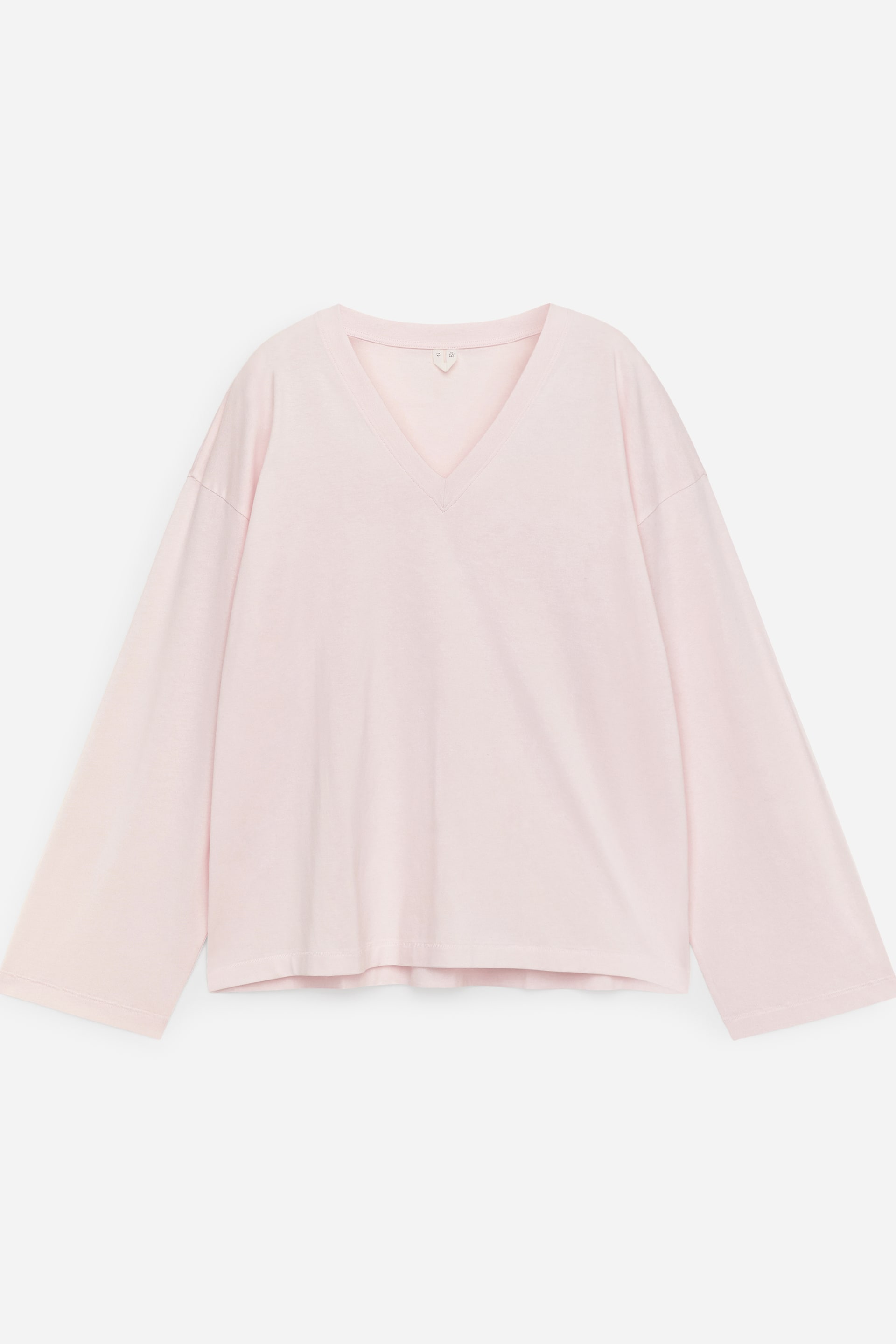 Visa större bild: En ljusrosa, löst sittande långärmad T-shirt visar sin framsida, med en ribbad V-ringning och vida ärmar som avslutas i raka fållar.