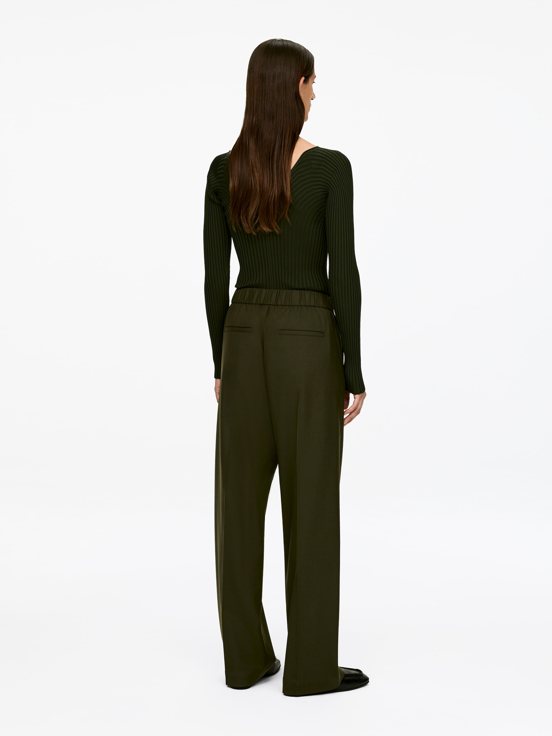 Ver imagen más grande: Una blusa de manga larga de color verde oscuro con canalé y unos pantalones anchos de color verde oliva oscuro se están mostrando, presentados desde atrás. La blusa muestra un escote en V en la parte trasera, y los pantalones están caracterizados por una cintura elástica y bolsillos de ribete traseros.
