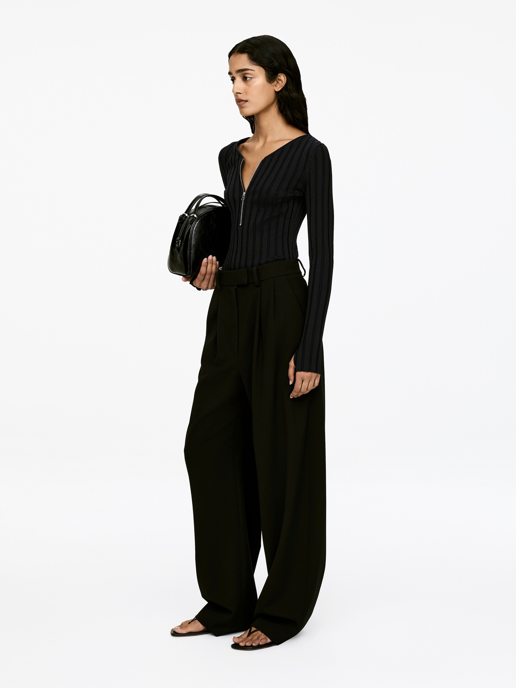 View larger image: A long-sleeved jumper, crafted from rib-knit fabric and featuring a slim-fit style with a half zip at the center front, is being worn by the model. The model is pairing the jumper with wide-leg trousers.