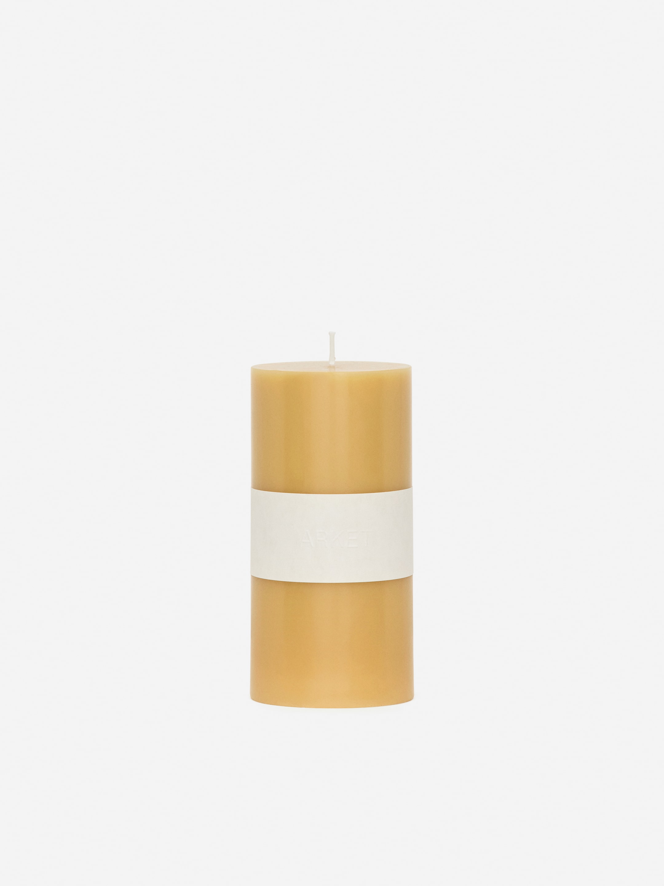 Visualizza immagine più grande: Una candela a colonna cilindrica è in piedi, rivolta in avanti, apparendo in un colore marrone chiaro o beige. Uno stoppino bianco si estende dalla sua superficie superiore e una fascia bianca è avvolta intorno al suo centro.