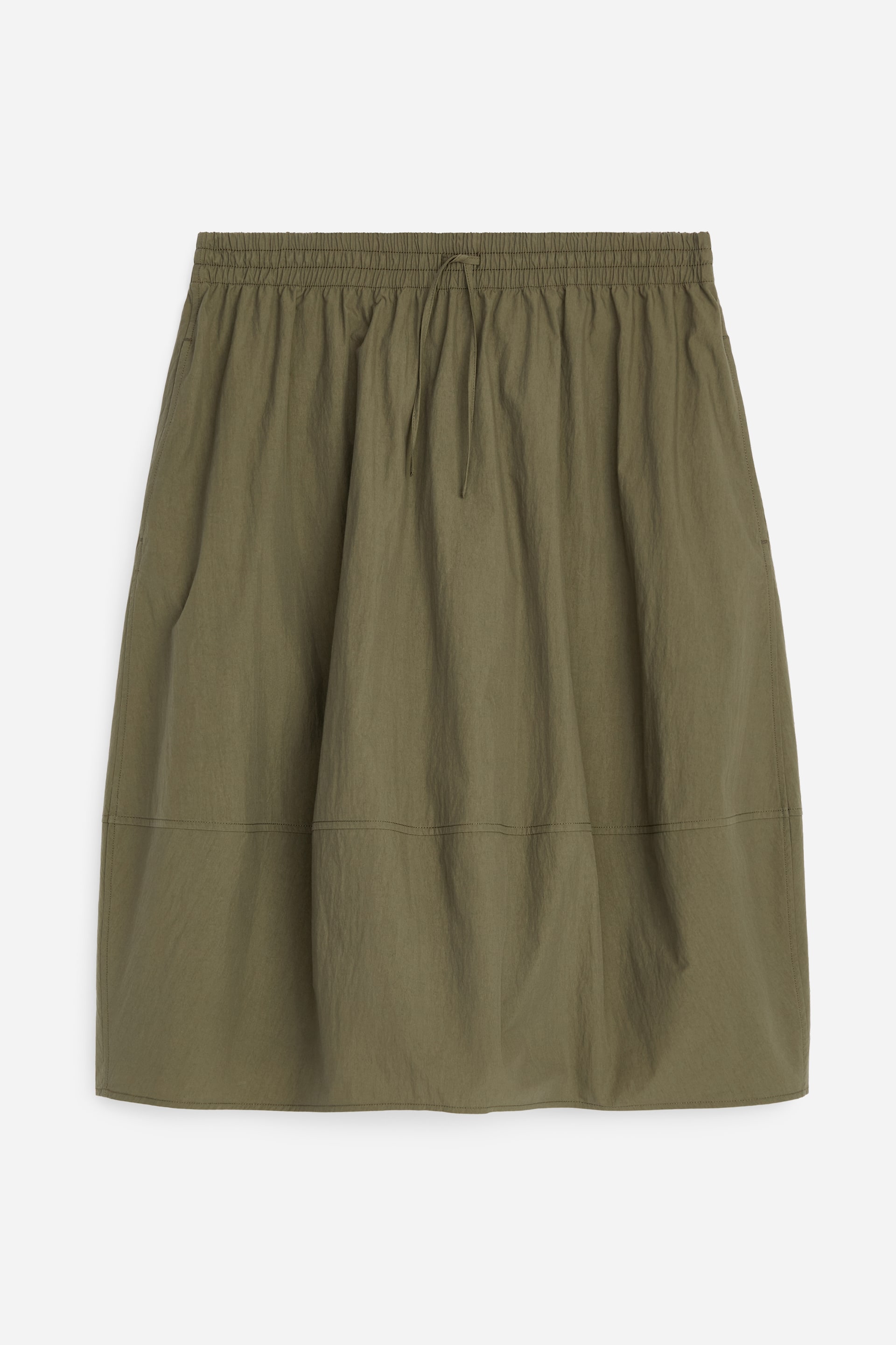 Zobrazit větší obrázek: Olivově zelená midi sukně je prezentována zepředu, ukazující siluetu kokonu s jemným objemem u lemu. Je vybavena elastickým pasem s tkanicí ze stejného materiálu, horizontálním švem nad lemem a otvorem pro kapsu na levém bočním švu.