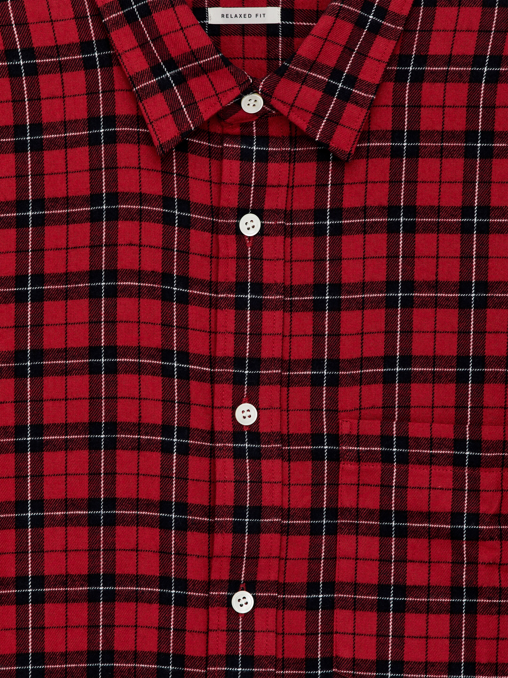 Visualizza immagine più grande: Una camicia di flanella di cotone a quadri rossi, neri e bianchi è esposta dal davanti. Presenta una tasca singola sul petto, bottoni in madreperla e un'etichetta 'RELAXED FIT' visibile sul colletto.