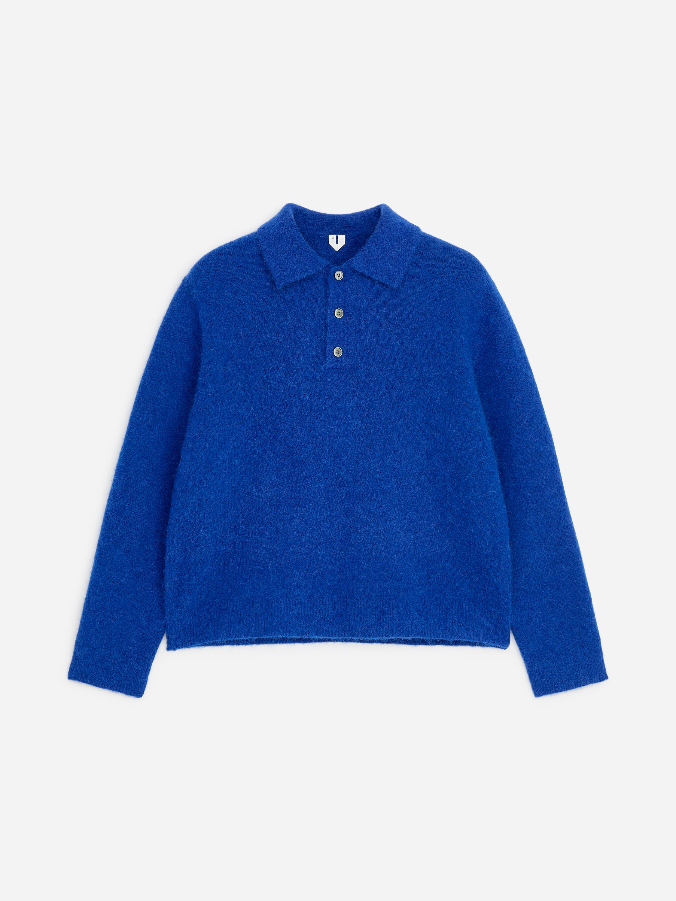 Model ma na sobie jasnoniebieski, puszysty sweter polo z dzianiny, z koÅnierzykiem i trzema guzikami przy plisie. Sweter jest zaÅożony na biaÅy T-shirt i zestawiony z ciemnymi spodniami.