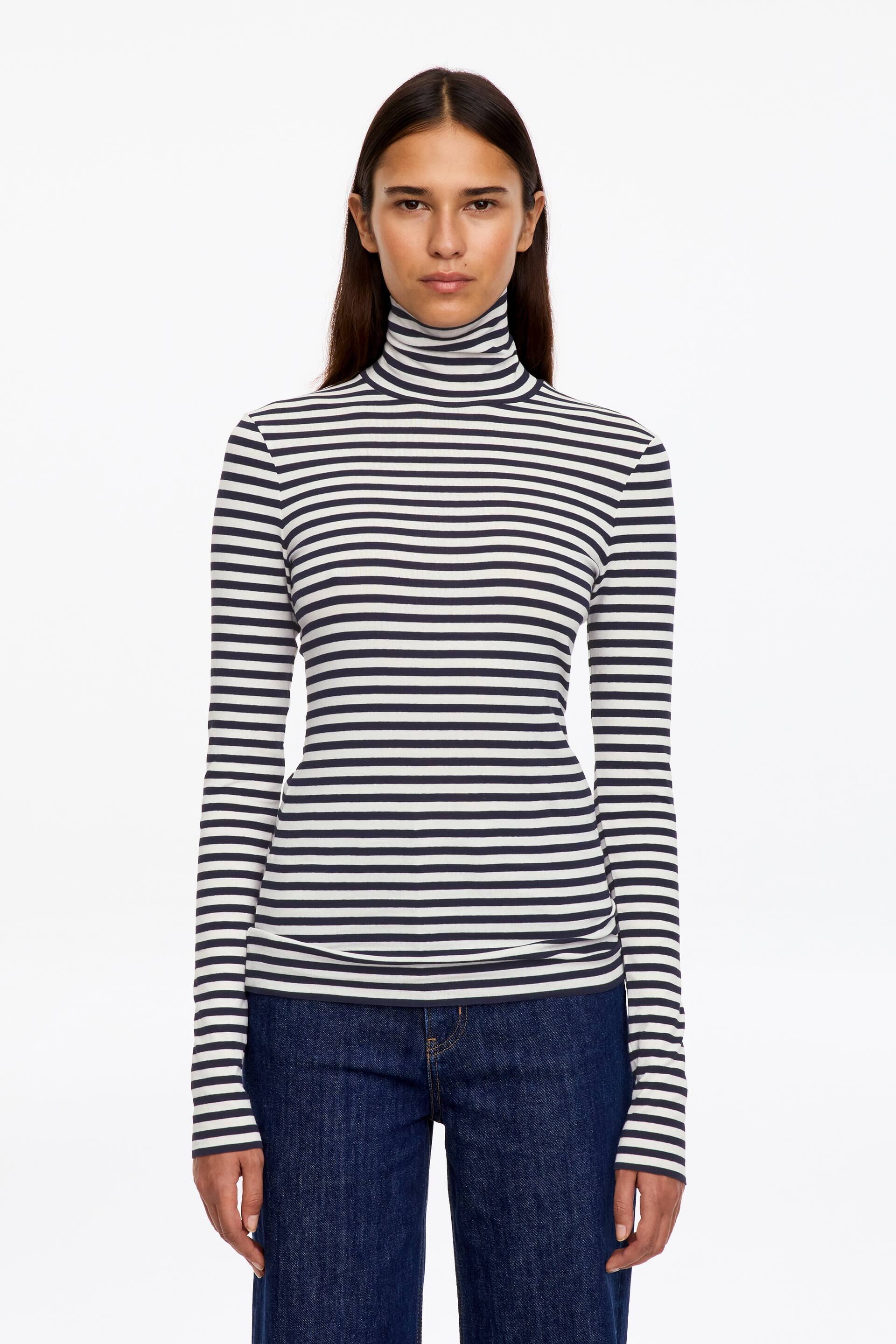 Größeres Bild ansehen: Ein langärmeliges Rollkragen-Jersey-Top mit dunklen und weißen horizontalen Streifen wird vom Model getragen. Das figurbetonte Oberteil ist mit dunkelblauen Denim-Jeans kombiniert.