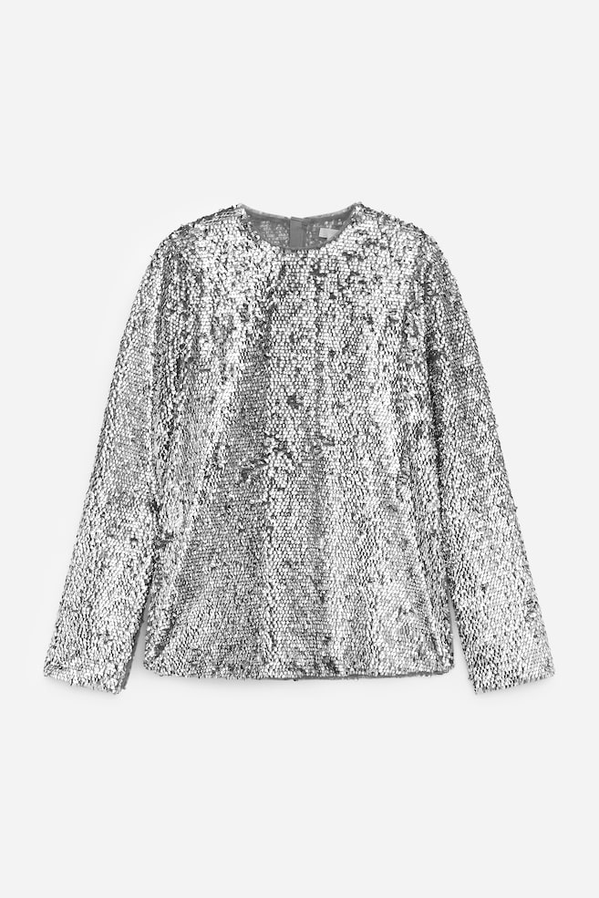 Se presenta una blusa de manga larga con lentejuelas plateadas desde el frente, con un escote redondo y un dobladillo recto. - 1