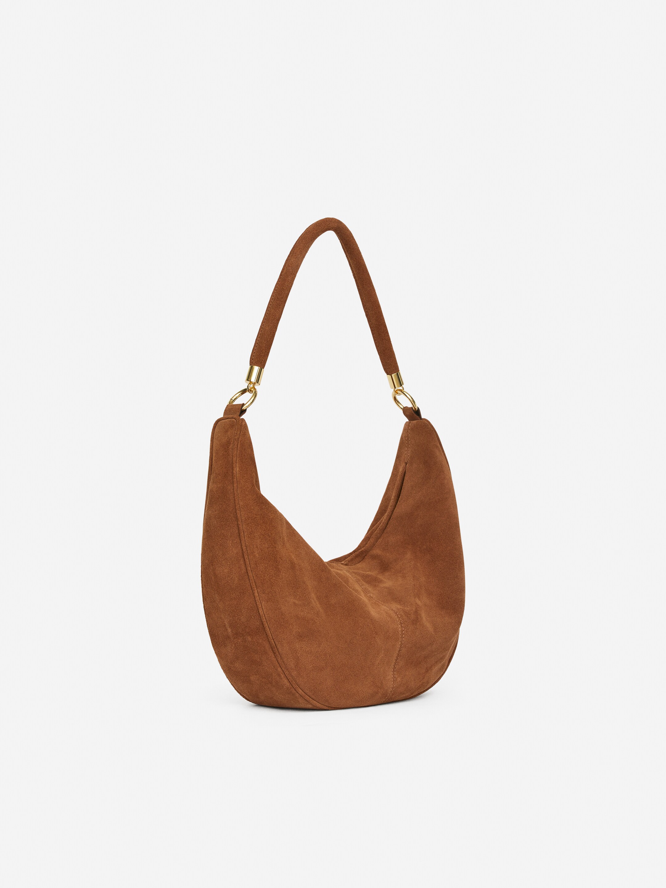 Grösseres Bild ansehen: Eine braune Schultertasche aus Wildleder wird präsentiert, die einen weichen, halbmondförmigen Körper und einen einzelnen Wildleder-Schulterriemen aufweist, der mit goldfarbenen Ringen befestigt ist.