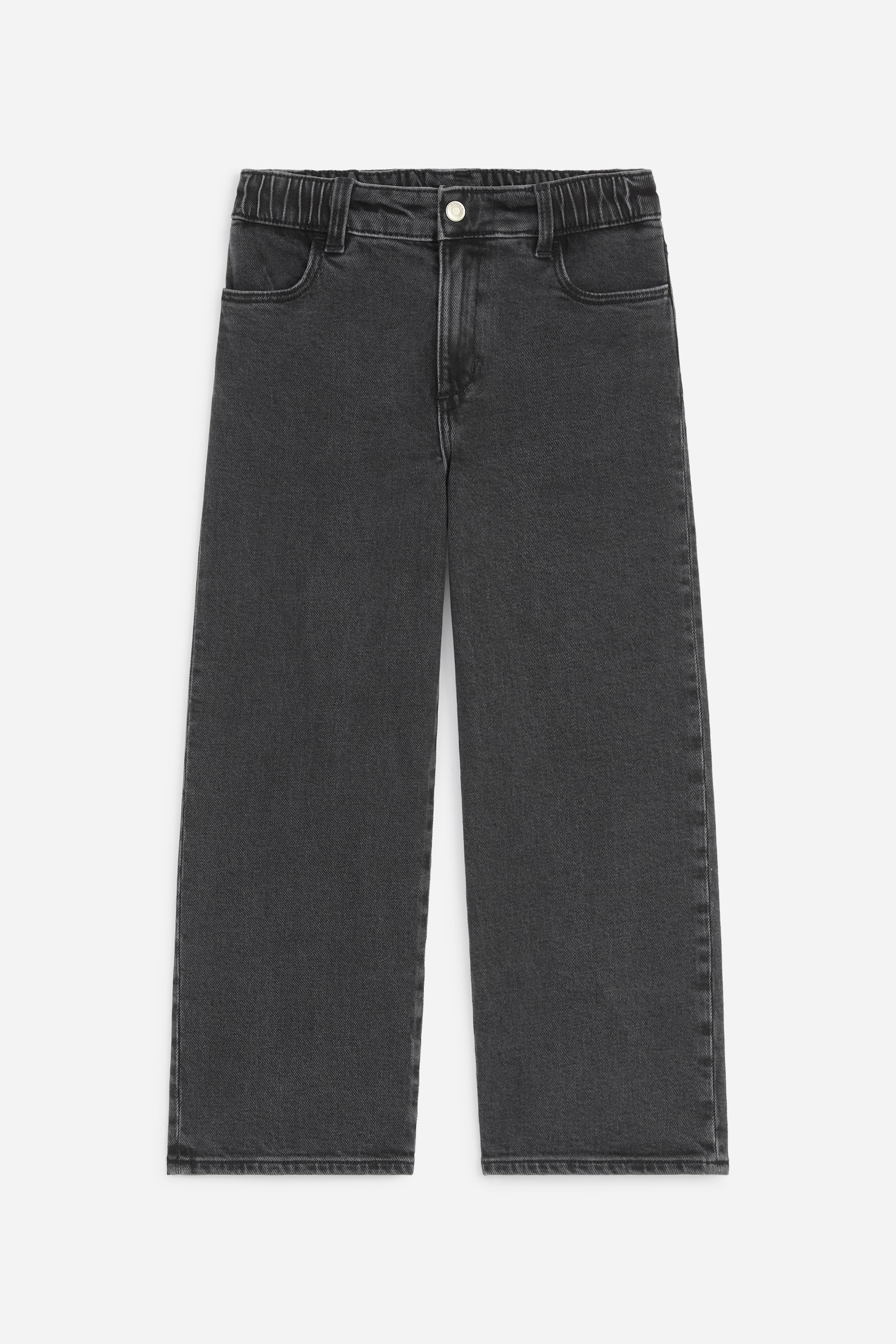 Ver imagem maior: Os jeans de perna larga em cinzento-escuro apresentam uma cintura elástica com fecho de um botão e dois bolsos frontais. Revelam um acabamento em denim lavado e uma perna direita e curta.