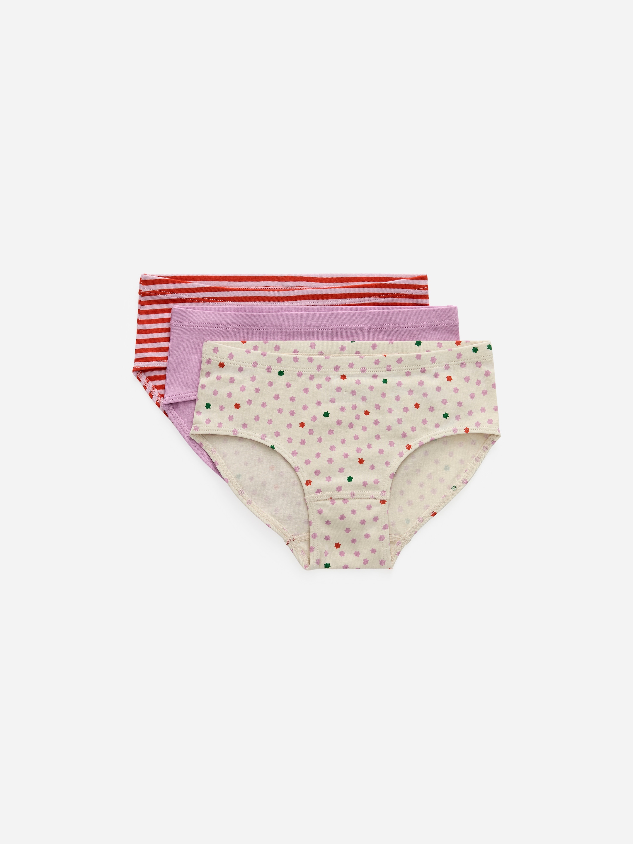 Agrandir l'image: Un ensemble de trois slips en coton est présenté, empilé l'un derrière l'autre et orienté vers l'AVANT. Le slip le plus à l'avant est crème avec des motifs d'étoiles multicolores dispersés, tandis que le slip derrière est d'un violet clair uni, et le slip le plus à l'arrière est rouge avec de fines rayures horizontales blanches.