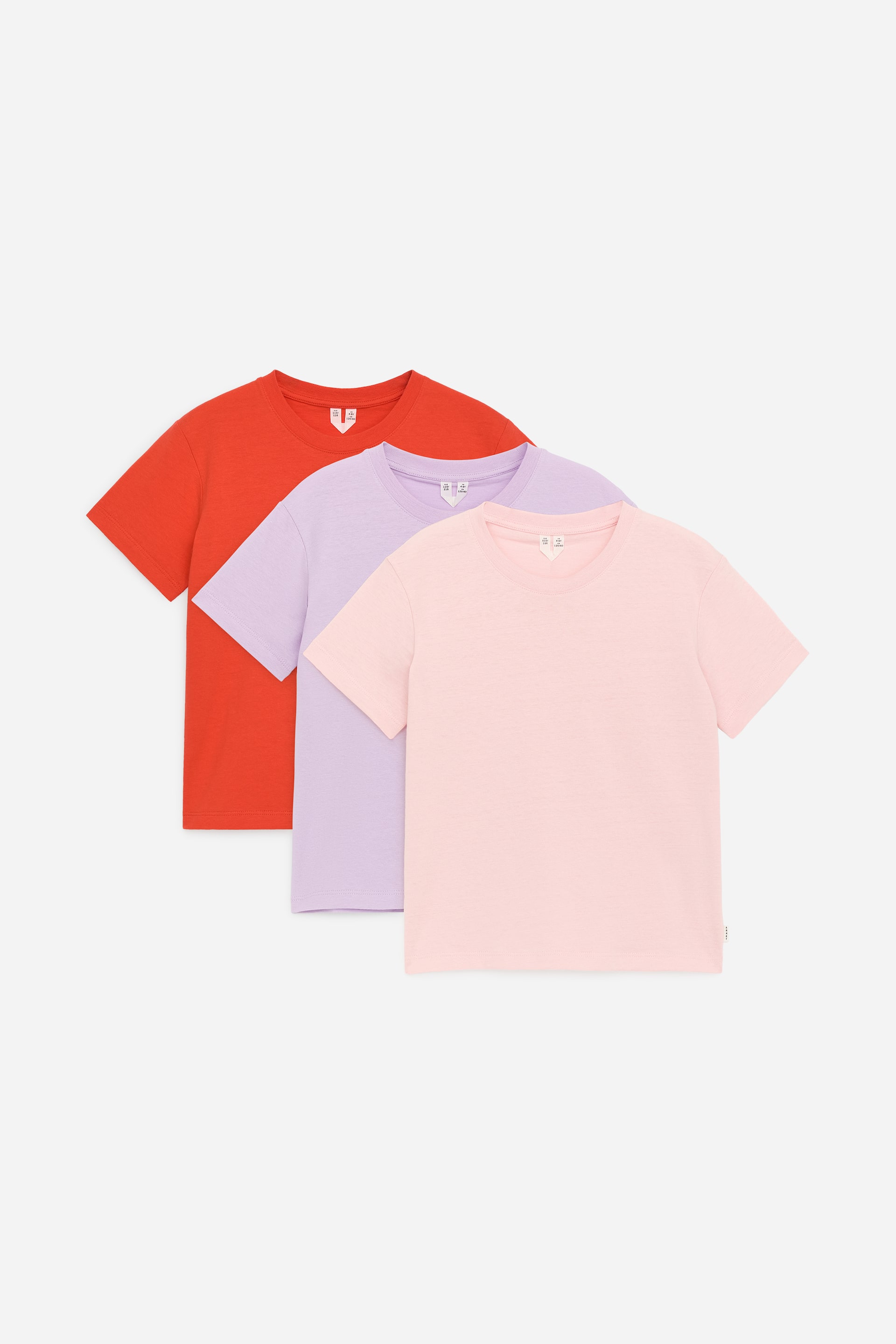 Visa större bild: Ett praktiskt set med tre bas-t-shirts i bomullsjersey presenteras, FRAMÅT, i ett lager-på-lager-arrangemang. T-shirtsen, designade för en normal passform med rund hals, visas i orange, ljuslila och ljusrosa.