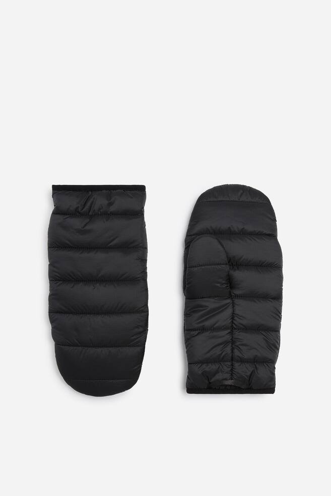 A pair of black puffer mittens is facing forward, featuring horizontal quilted baffling and a ripstop texture. The left mitten is showing the smooth back of the hand, while the right mitten is displaying the palm side with its thumb compartment. - 1