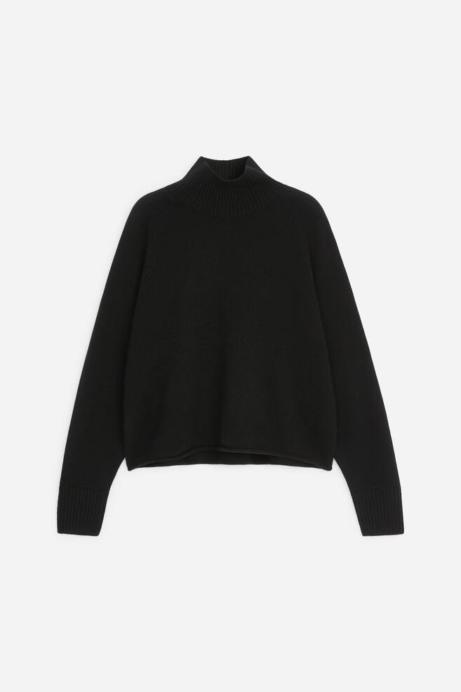 Ein schwarzer Strickpullover ist von vorn zu sehen und verfÃ¼gt Ã¼ber einen gerippten Stehkragen sowie lange Ãrmel mit breiten RippbÃ¼ndchen. Der Pullover zeigt eine lÃ¤ssige, kastige Silhouette mit einem sauberen, leicht aufgerollten Saum. - 1