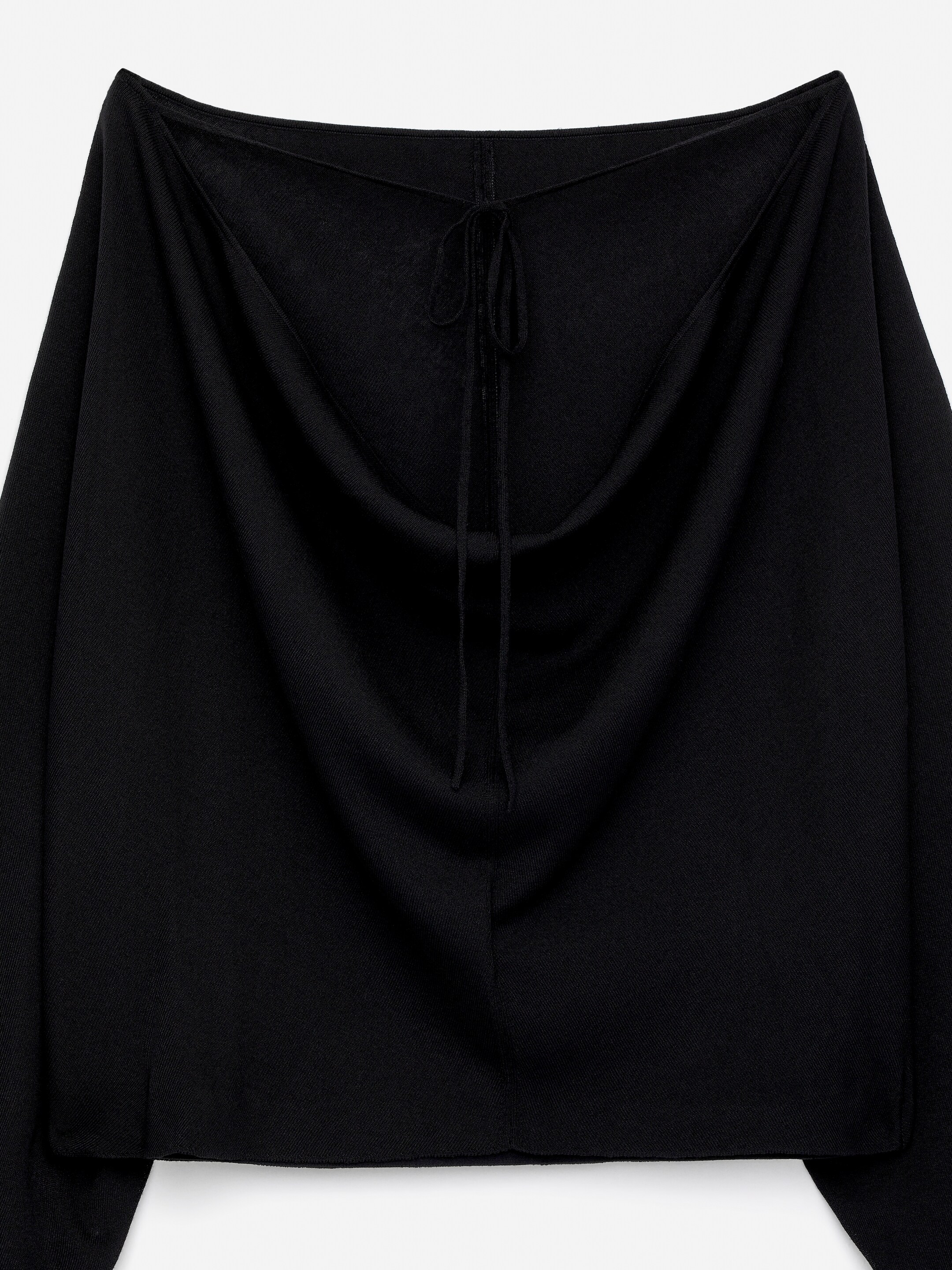 Agrandir l'image: Un haut noir à encolure bateau tricoté dans un mélange de lyocell met en valeur son DOS. Ce style ample présente un dos ouvert avec des cordons à nouer à l'arrière du cou.