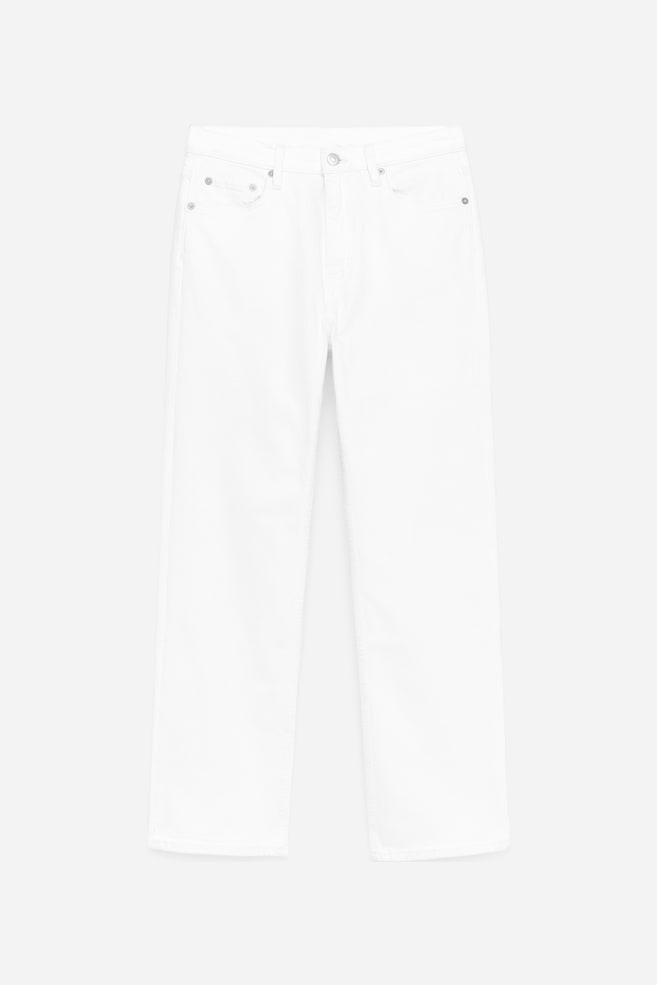 I jeans bianchi sono mostrati frontalmente, presentando una vita a metà altezza, una silhouette slim e gambe affusolate e corte, con una zip frontale visibile e tasche anteriori. - 1