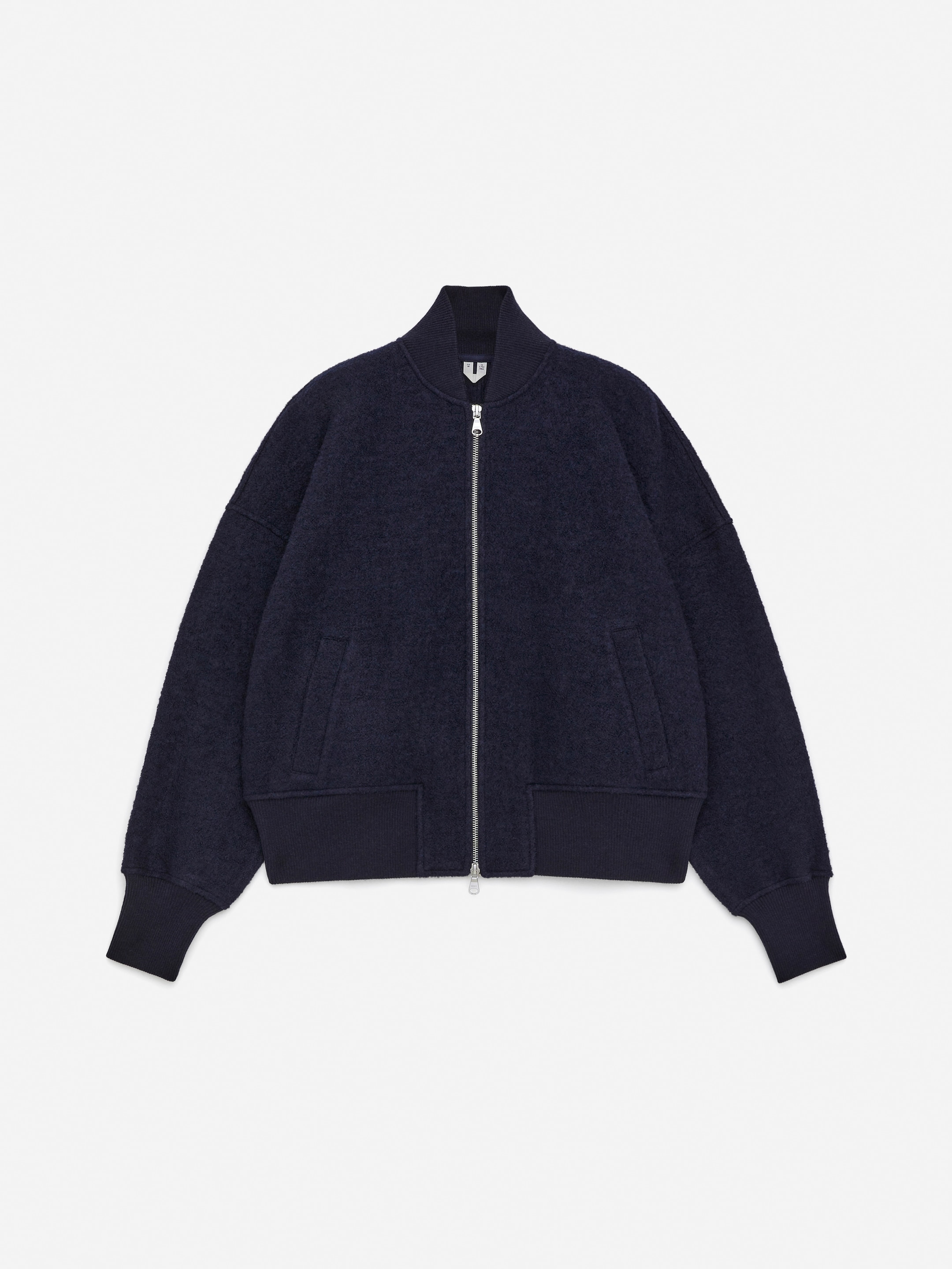 Größeres Bild anzeigen: Eine dunkelblaue Jacke wird von vorne präsentiert, mit überschnittenen Schultern und einer strukturierten Oberfläche. Sie ist mit einem Zwei-Wege-Reißverschluss, zwei vorderen Leistentaschen und gerippten Abschlüssen am Kragen, an den Bündchen und am Saum gestaltet.