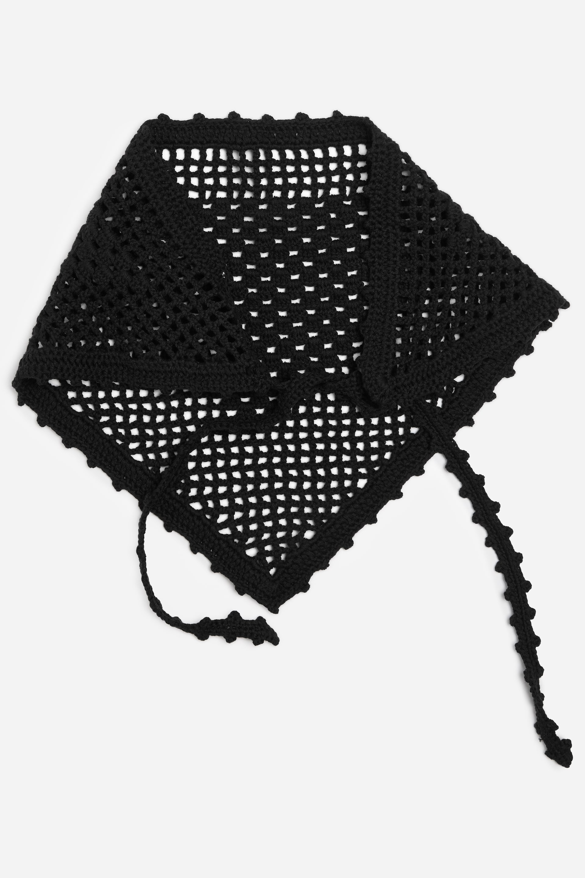 Agrandir l'image: Un fichu noir en crochet présente un motif ajouré, semblable à un filet. Il affiche une forme triangulaire avec des bords festonnés et deux longues attaches ornées de détails en boules.