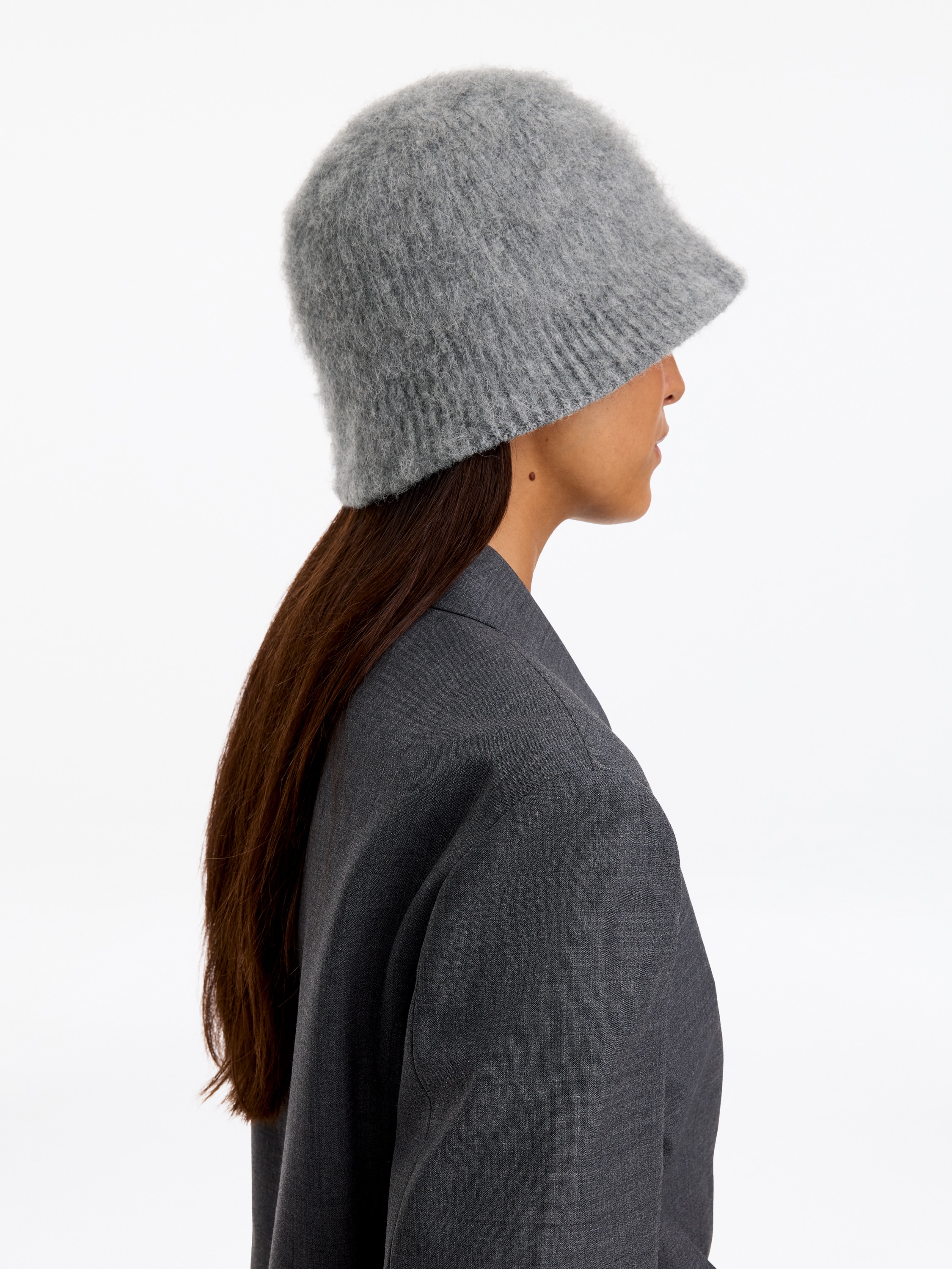 Een gebreide bucket hat in gemÃªleerd grijs is van voren gericht en toont een zachte, pluizige textuur en een geribbelde gebreide rand.