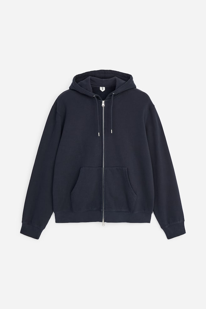 Un sweat à capuche zippé bleu marine foncé est présenté de face, avec une double fermeture éclair argentée, une capuche ajustable avec cordons assortis et une poche kangourou fendue. Ce sweat à capuche à manches longues est fini avec des poignets côtelés et un ourlet côtelé. - 1