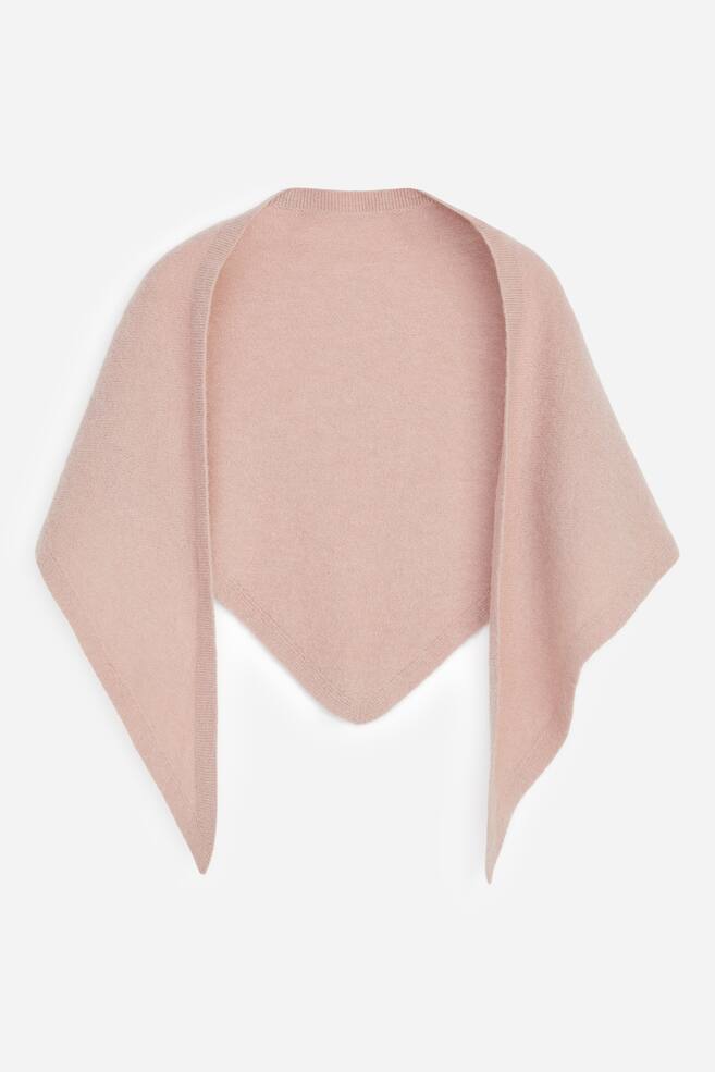 Una bufanda de punto rosa pÃ¡lido cae en forma triangular, mostrada de frente con un fino borde acanalado a lo largo de los bordes. La bufanda luce una textura suave, con un centro en punta y dos extremos largos y afilados colgando. - 1