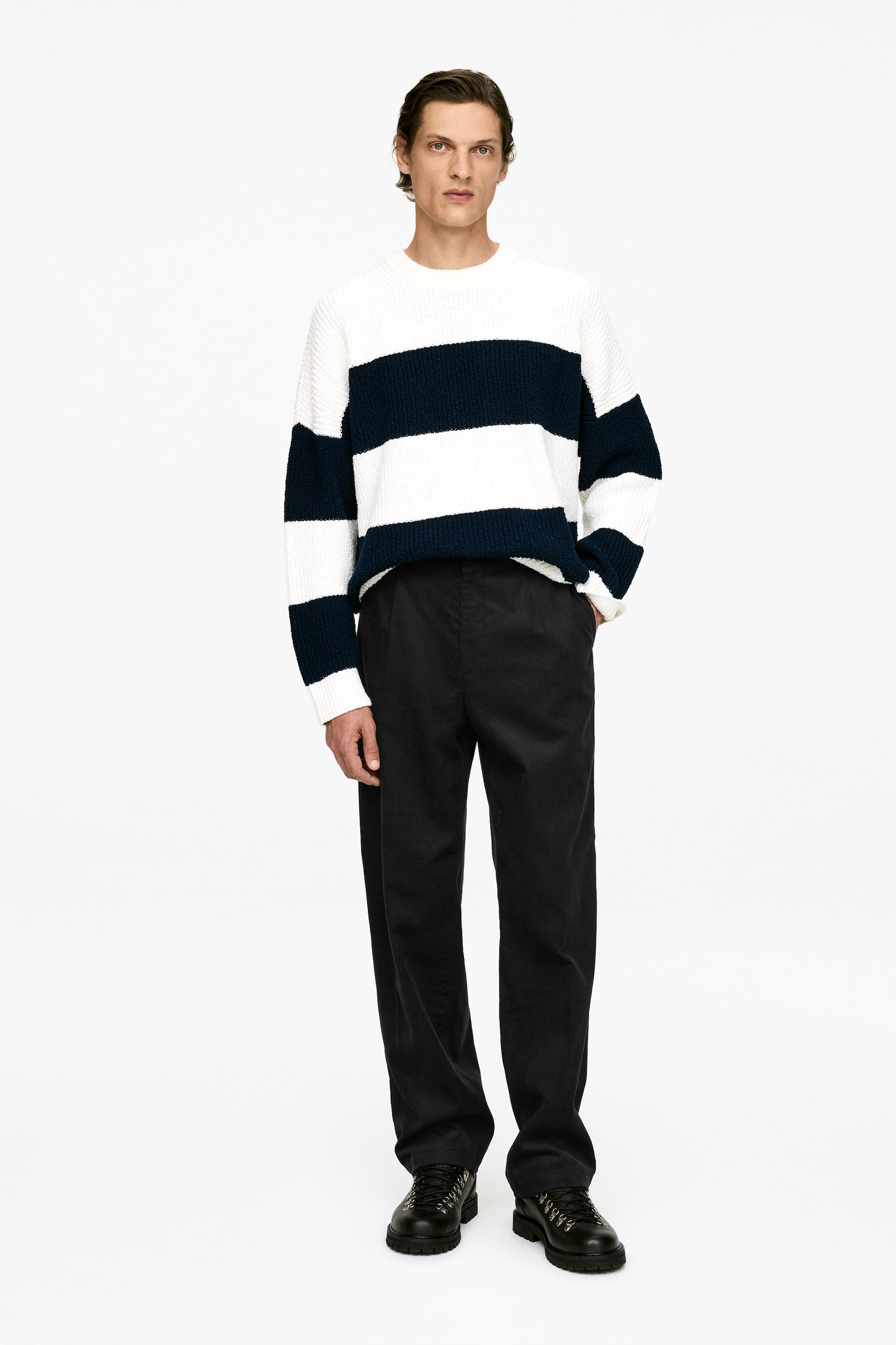 Vezi imaginea mai mare: Pantaloni din catifea neagră, cu o croială lejeră, având picioare drepte și buzunare laterale, sunt purtați de model.