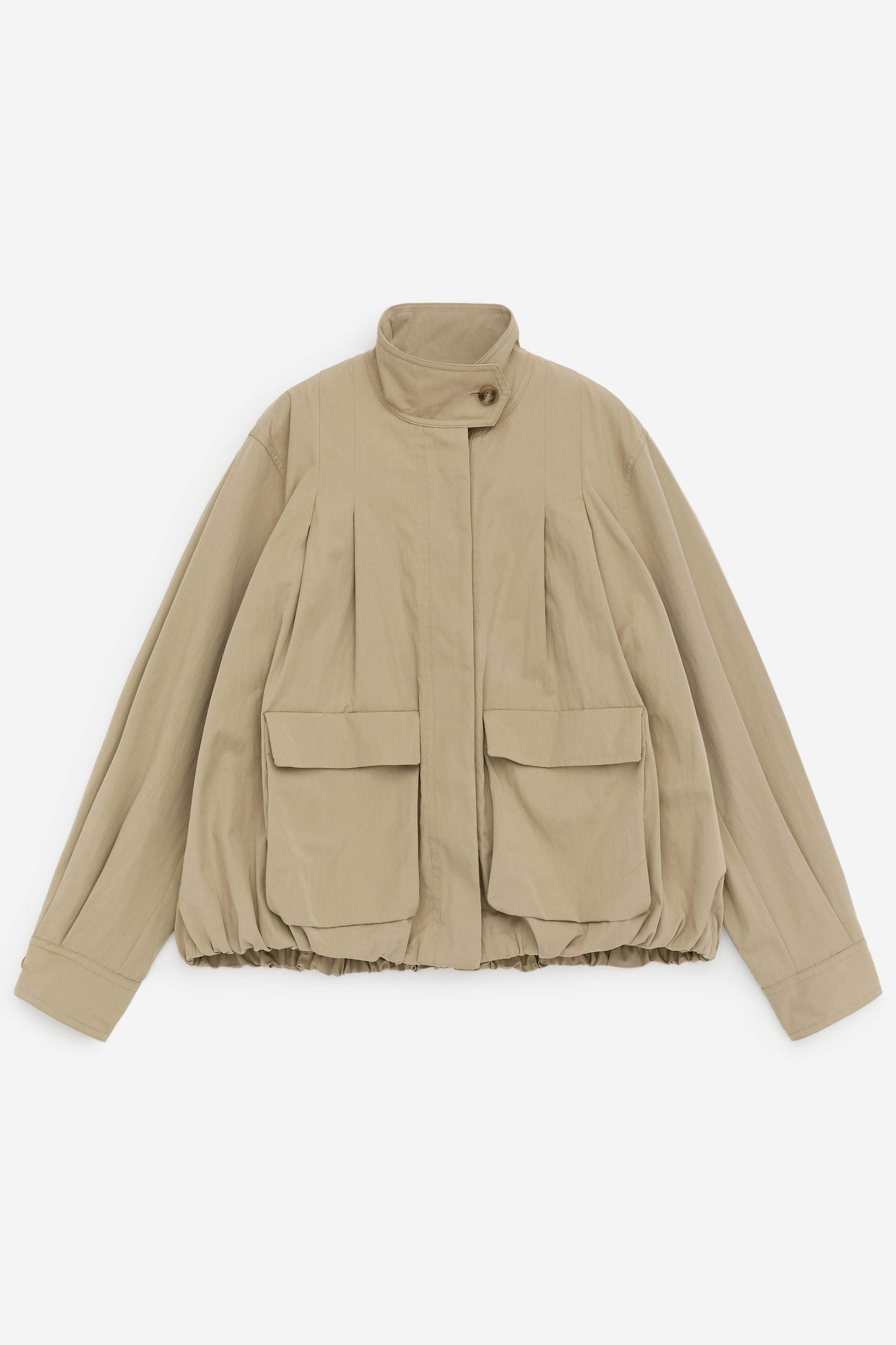 Visualizza l'immagine ingrandita: Una giacca beige è presentata nella sua vista FRONTALE, caratterizzata da un colletto alla coreana con una chiusura a bottone singolo visibile al collo. Presenta due grandi tasche a toppa con patta sul davanti inferiore, pieghe verticali sulla parte superiore del davanti e maniche lunghe con polsini abbottonati, il tutto sopra un orlo elasticizzato arricciato.