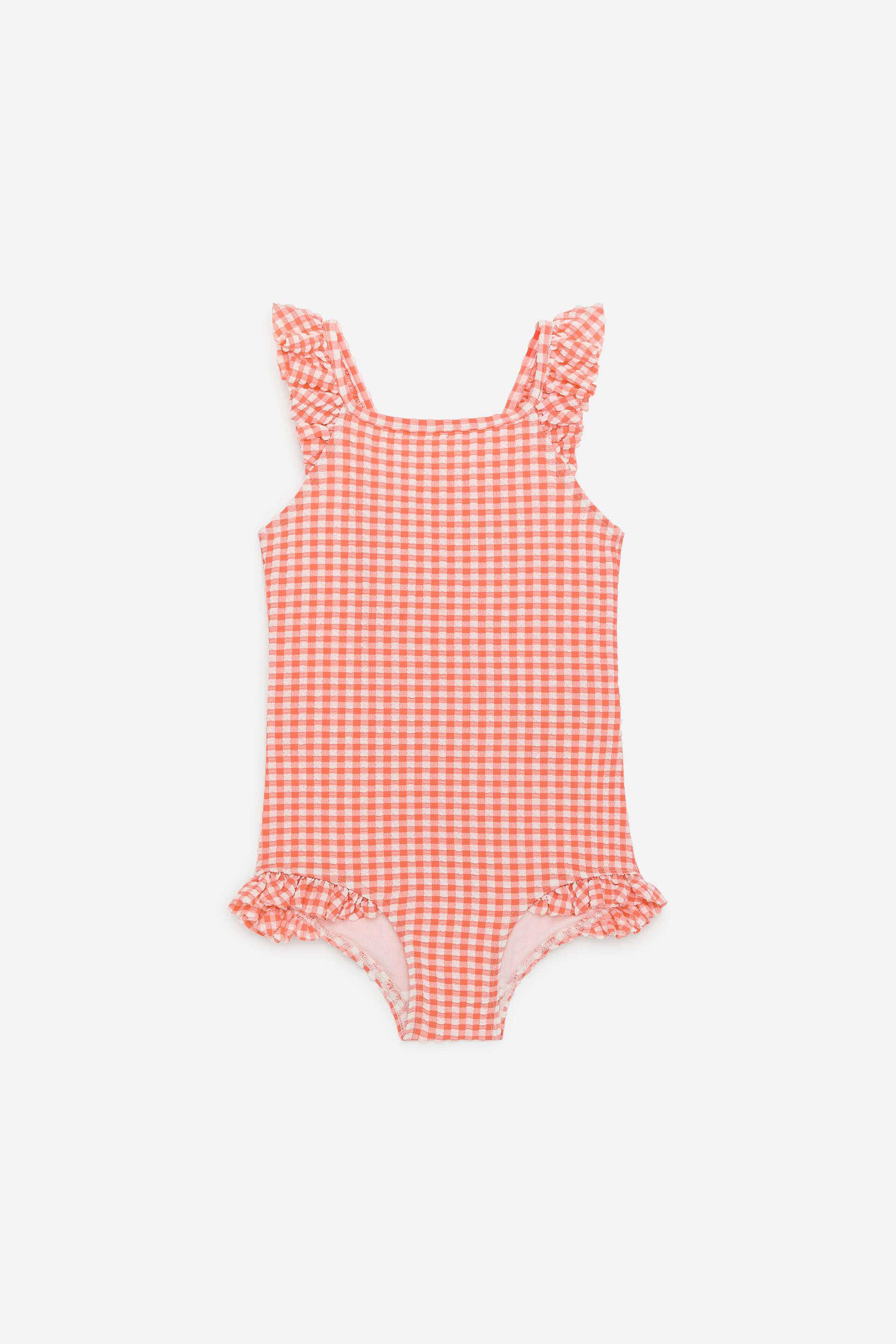 Se større billede: En badedragt viser sin forside, lavet af et rød- og hvidternet garnfarvet jersey seersucker-stof. Den har flæsedetaljer ved skuldrene og benåbningerne og har en almindelig pasform.