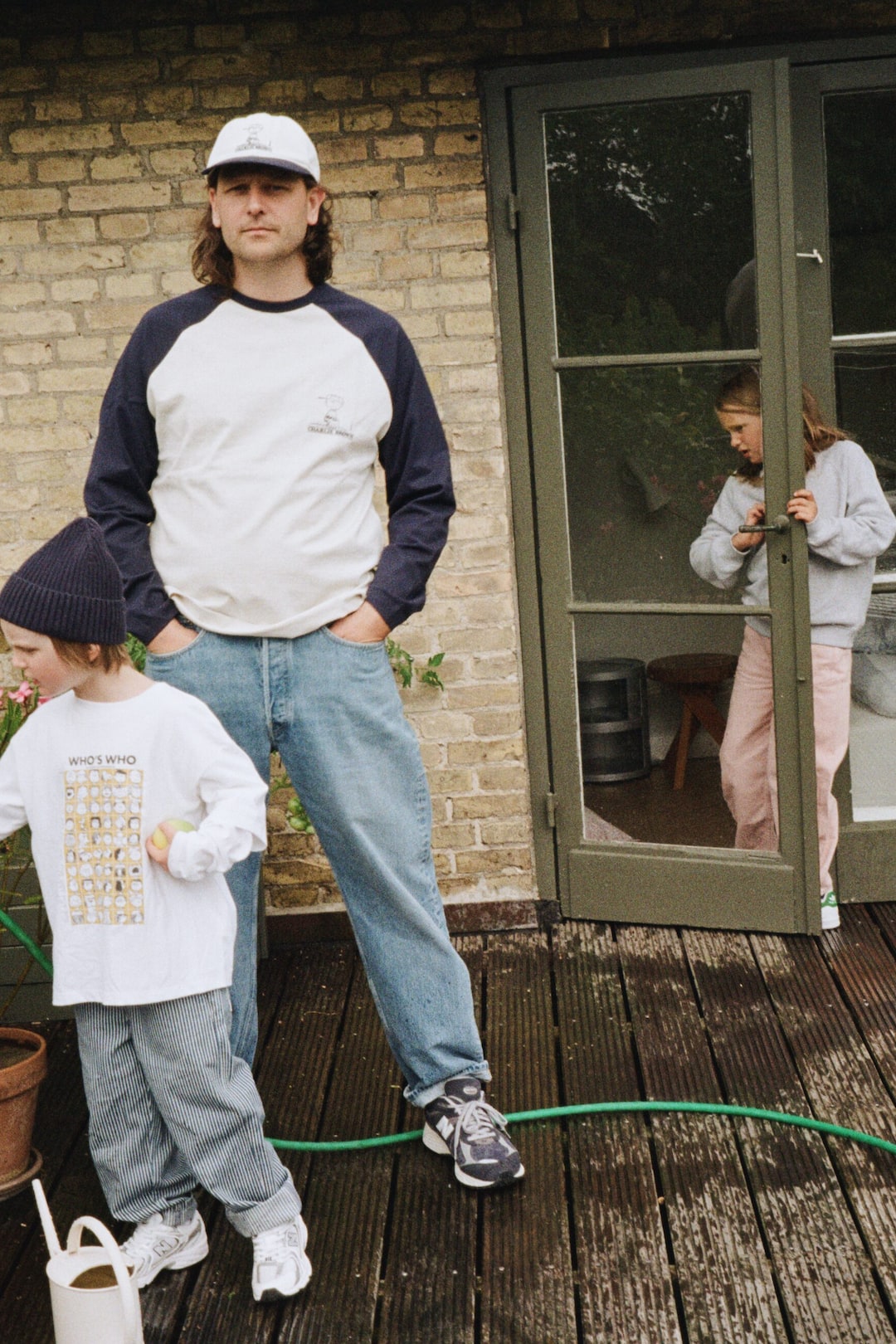 Visa större bild: En vit långärmad t-shirt för barn med ett rektangulärt grafiskt tryck på framsidan av bröstet, med ett rutnät av små illustrationer och texten "WHO'S WHO" ovanför dem.