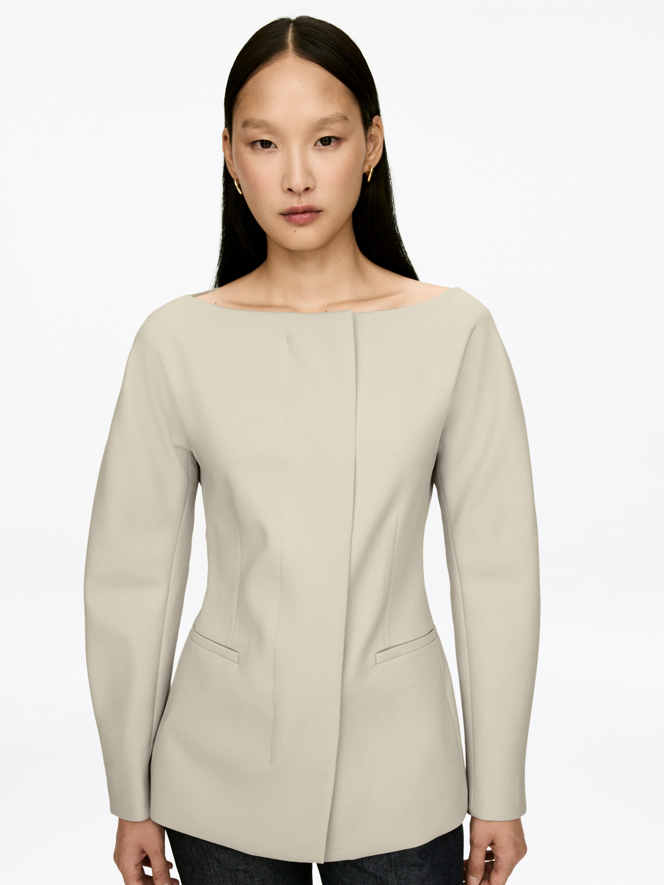 Agrandir l'image: Une veste beige clair est présentée de face, avec un large col bateau et des manches longues. La veste est conçue avec un panneau avant structuré et deux poches passepoilées horizontales, s'étendant au-delà des hanches.