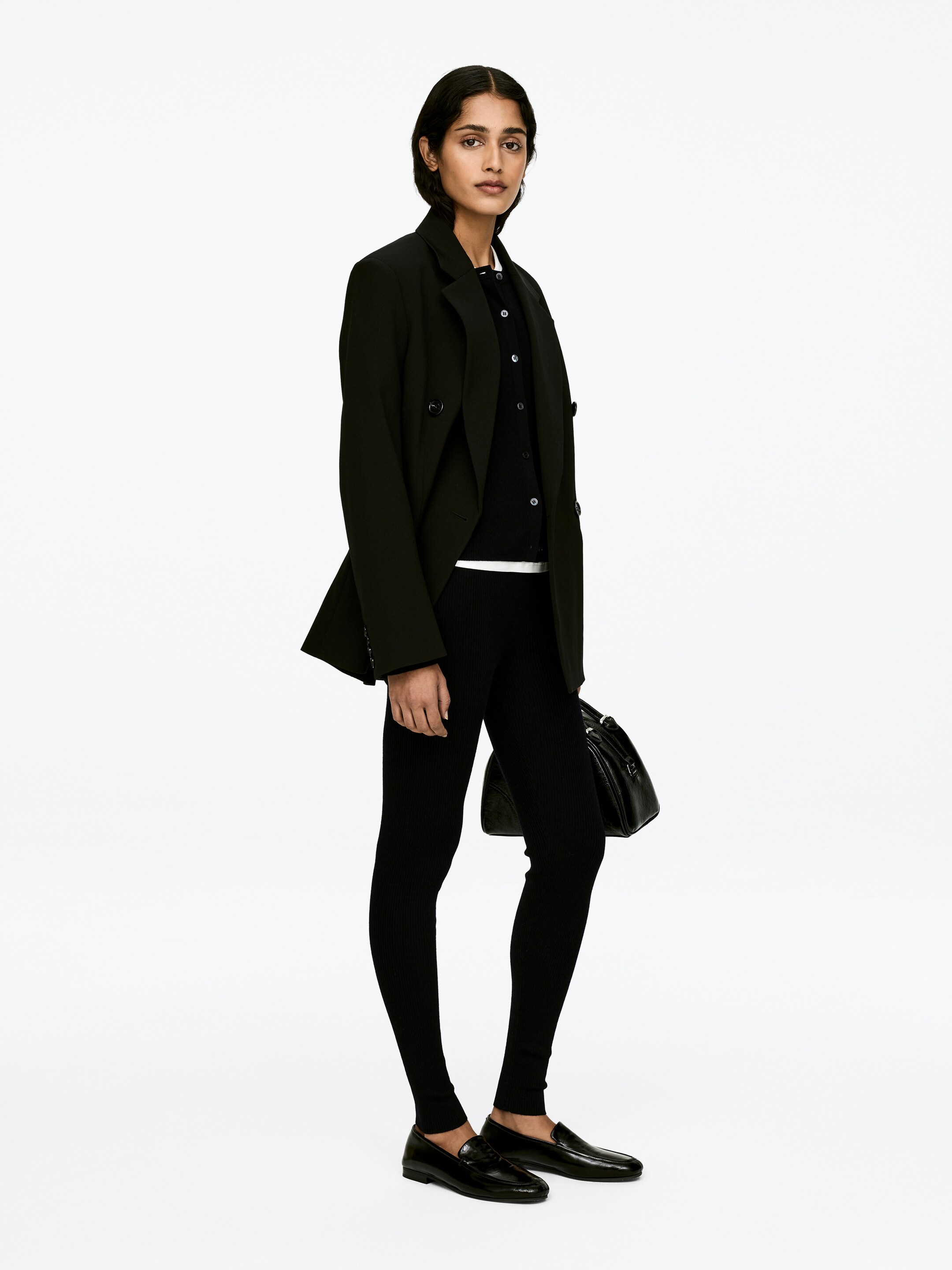 Zobacz większy obraz: Czarne, prążkowane legginsy są noszone przez modelkę. Obcisłe legginsy ukazują wyraźną prążkowaną teksturę i sięgają do kostek.