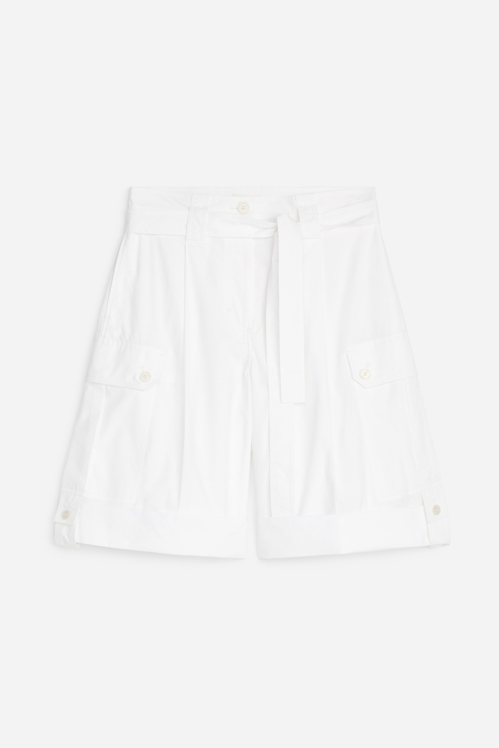 Visualizza immagine più grande: I pantaloncini bianchi ispirati all'utilità si presentano frontalmente, caratterizzati da una fascia a nodo in vita, una chiusura a bottone e una zip. Grandi tasche laterali con patte sono visibili su entrambi i lati, e i passanti in tessuto con chiusure a bottone a pressione dettagliando l'orlo inferiore, contribuendo a una vestibilità rilassata.