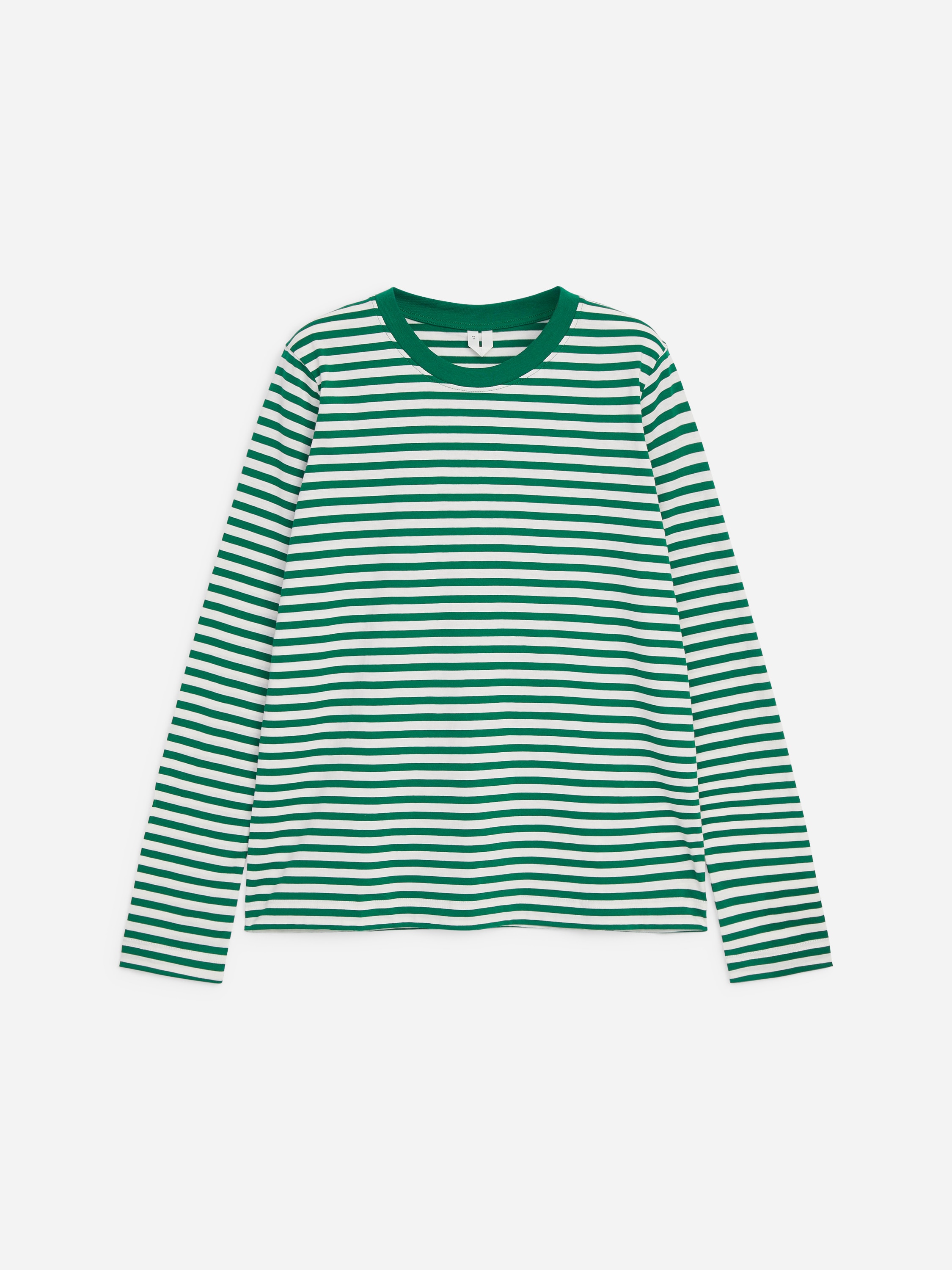 Modelul poartă un tricou cu mânecă lungă, cu dungi orizontale verzi și albe, și cu guler rotund verde uni, din material rib cu bordură. Modelul asortează cămașa cu croială regular fit cu blugi din denim albastru, având o mână băgată în buzunar.